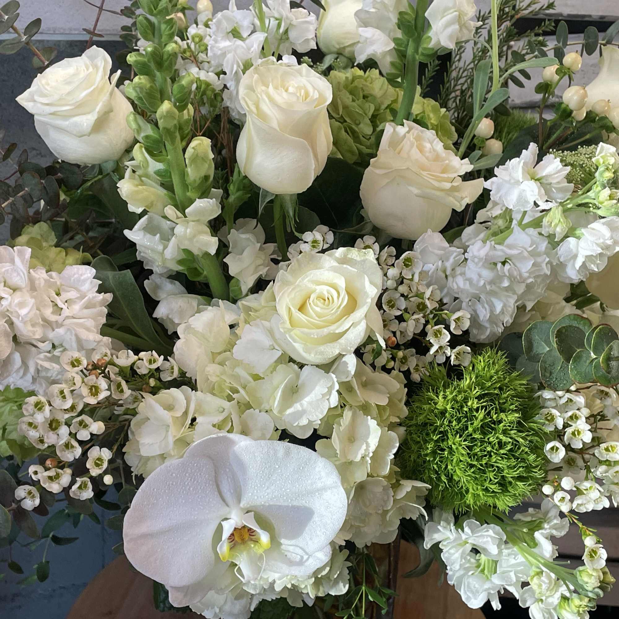 Standing tall and lushly filled with all white roses, hydrangea, flowing eucalyptus