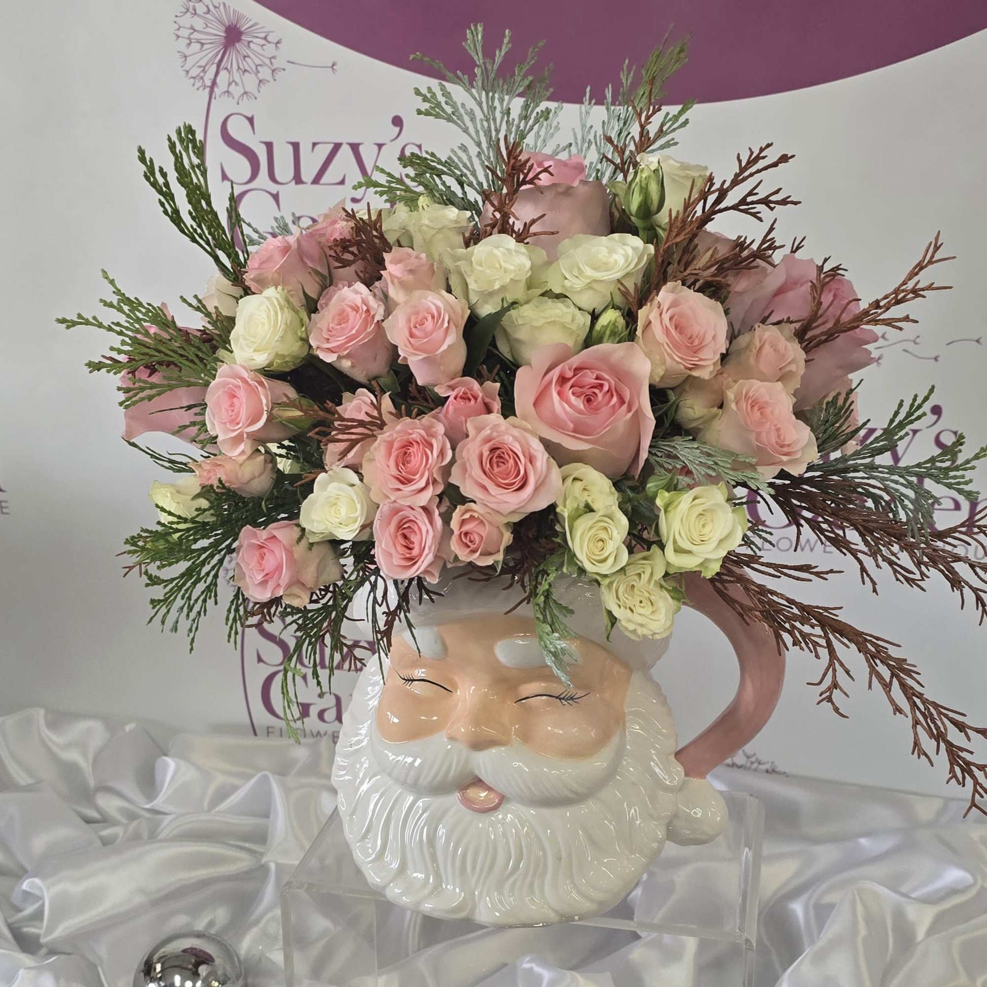 A festive Santa vase, Christmas flower arrangement featuring roses, surrounded by mixed