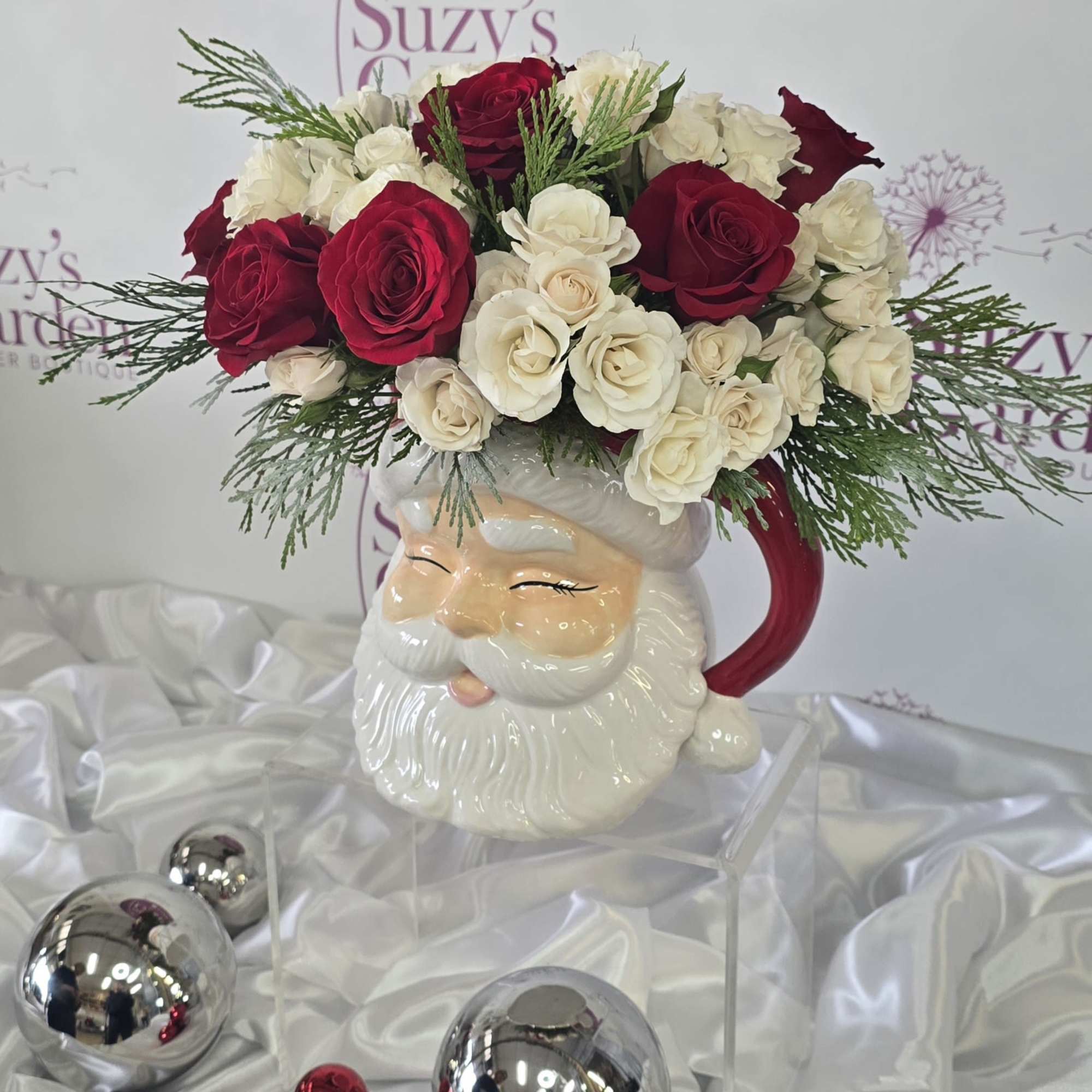 A festive Santa vase, Christmas flower arrangement featuring roses, surrounded by mixed