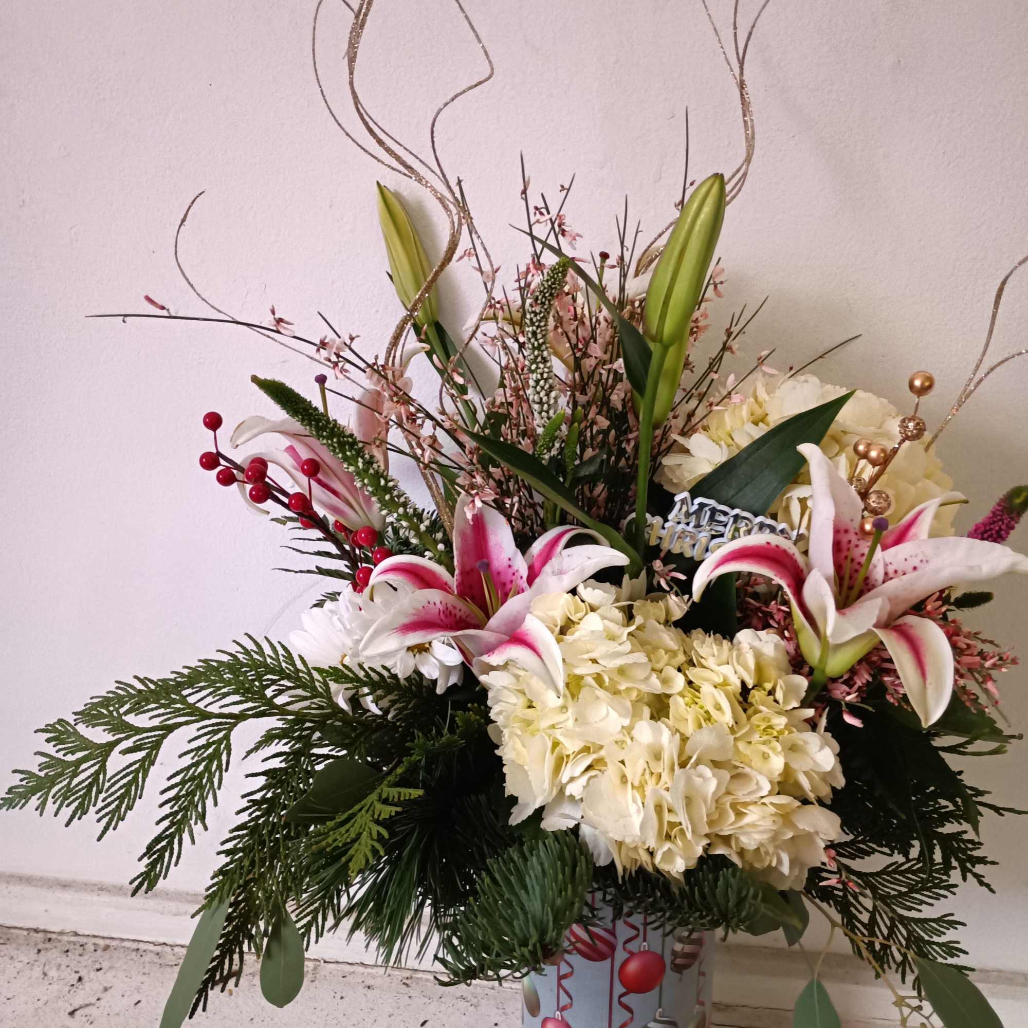 Festive Christas ornaments vase with varied Christmas greens, stargazer Lily, white hydrangea
