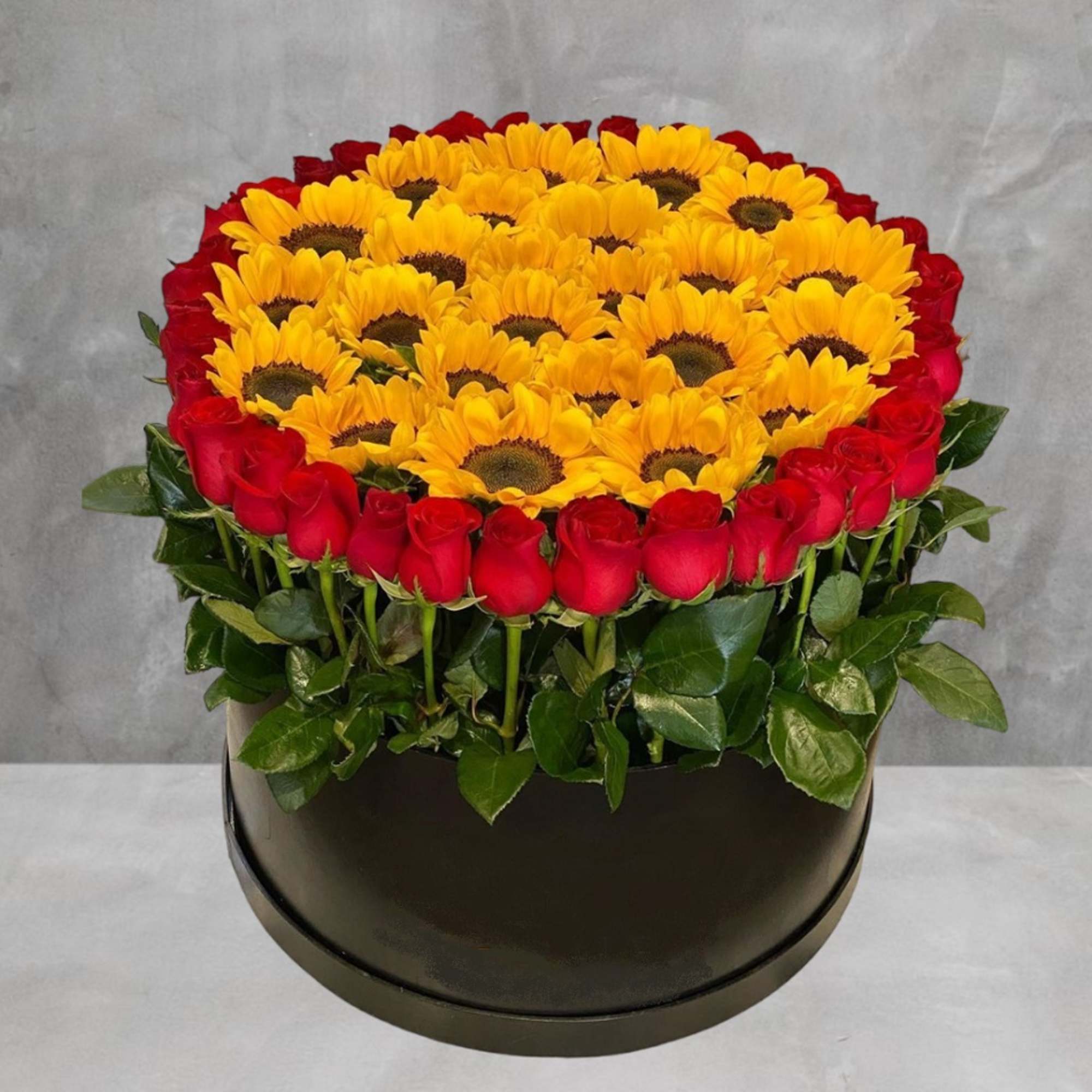 The Red Roses and Yellow Sunflowers Cylinder Arrangement will leave a lasting
