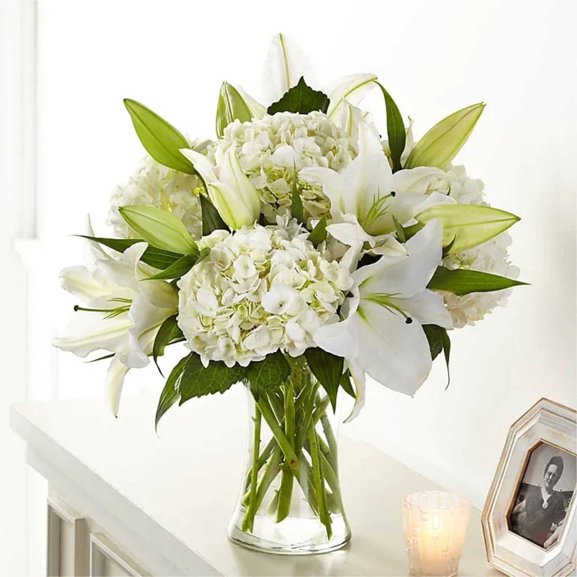 Classic lily and hydrangea blooms are arranged by our talented designers to