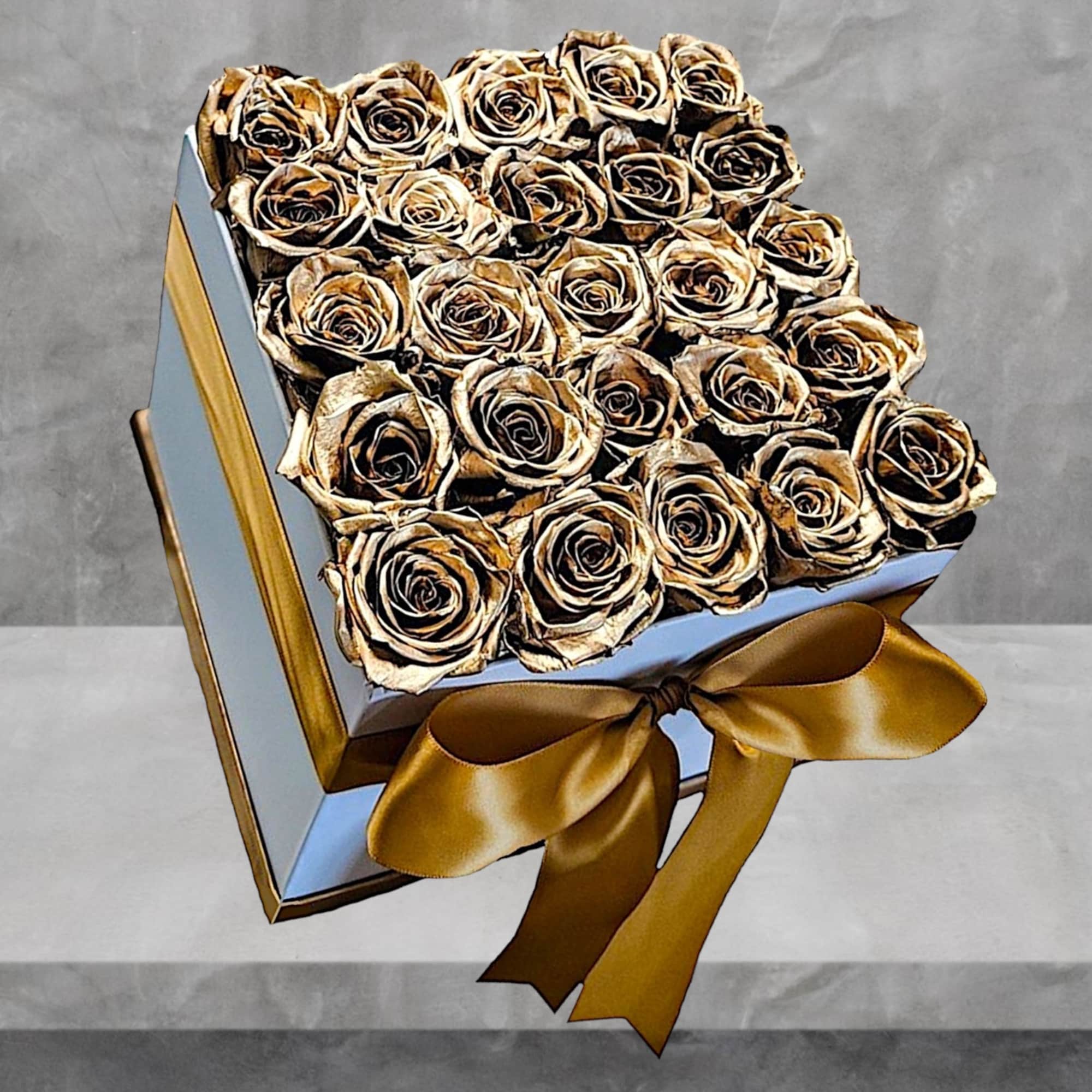 A modern flower arrangement in a white box filled with gold painted