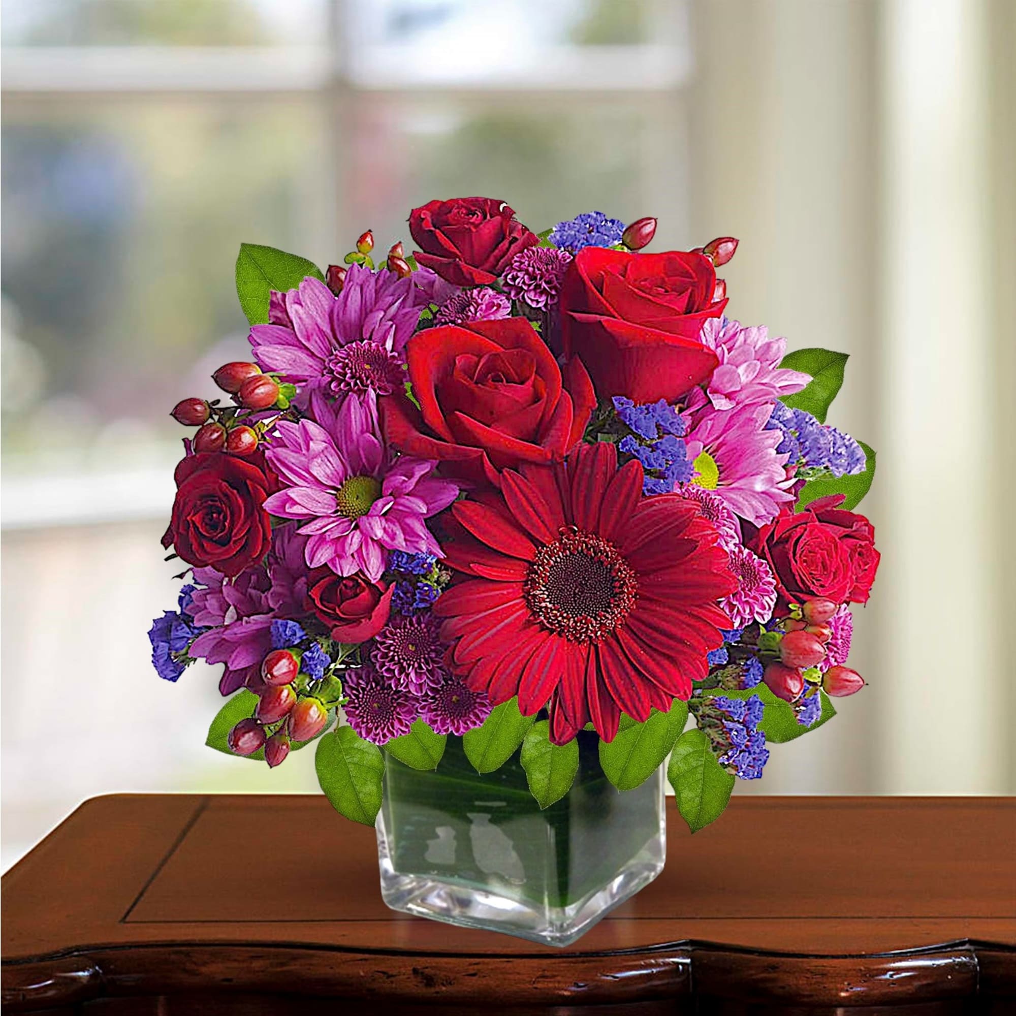 Rich jewel-toned flowers are arranged in a glass cube vase for a