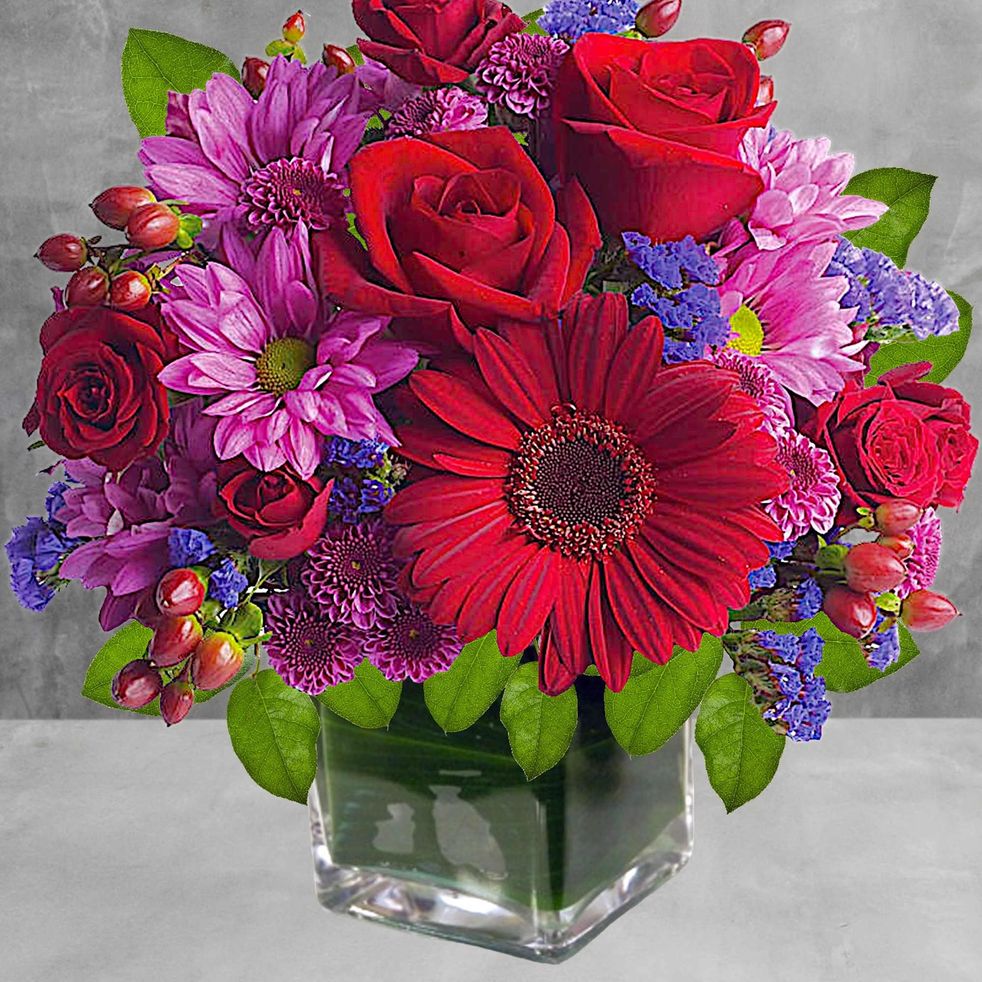 Rich jewel-toned flowers are arranged in a glass cube vase for a