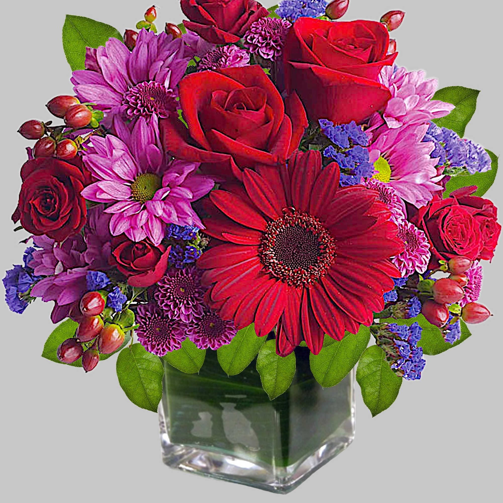 Rich jewel-toned flowers are arranged in a glass cube vase for a