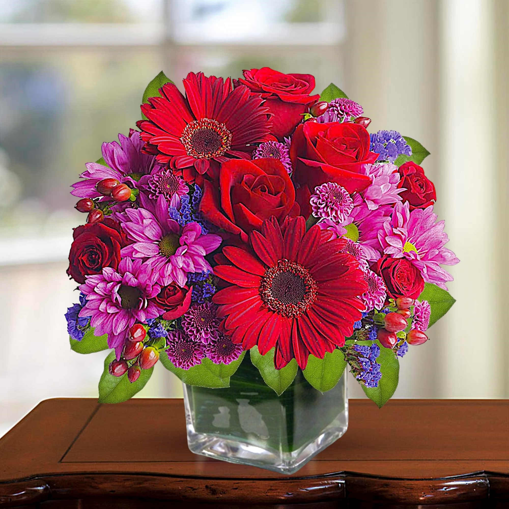 Rich jewel-toned flowers are arranged in a glass cube vase for a