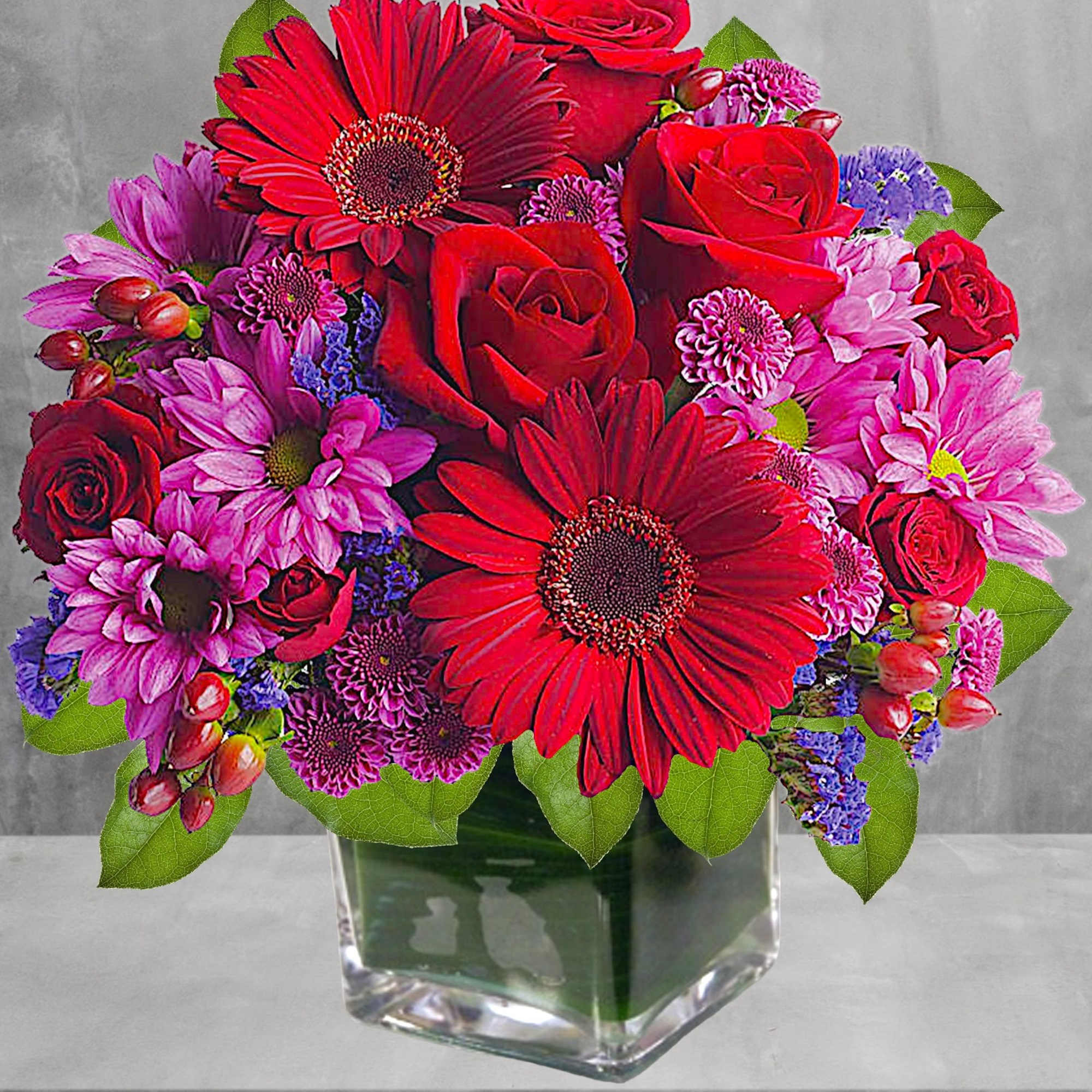 Rich jewel-toned flowers are arranged in a glass cube vase for a