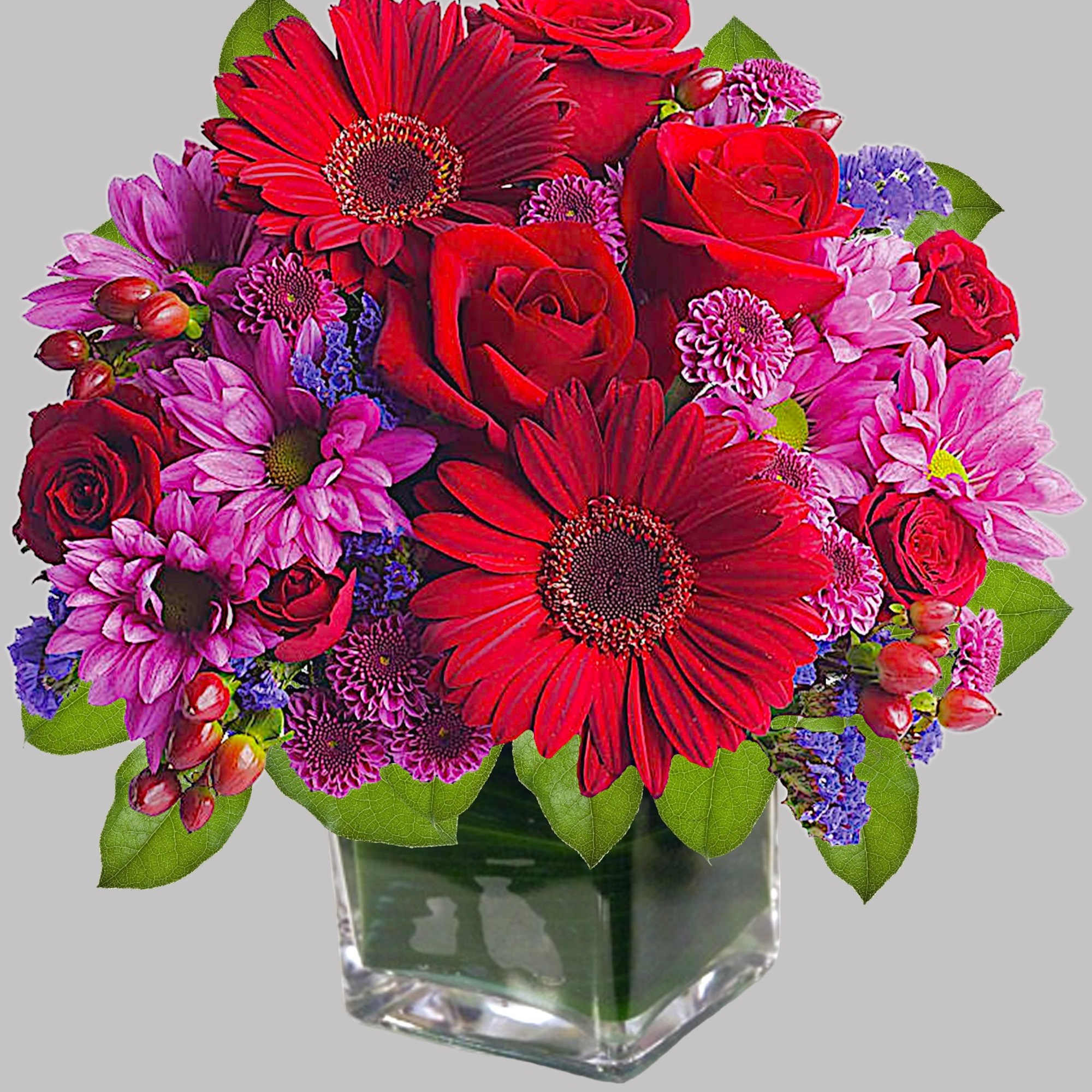 Rich jewel-toned flowers are arranged in a glass cube vase for a