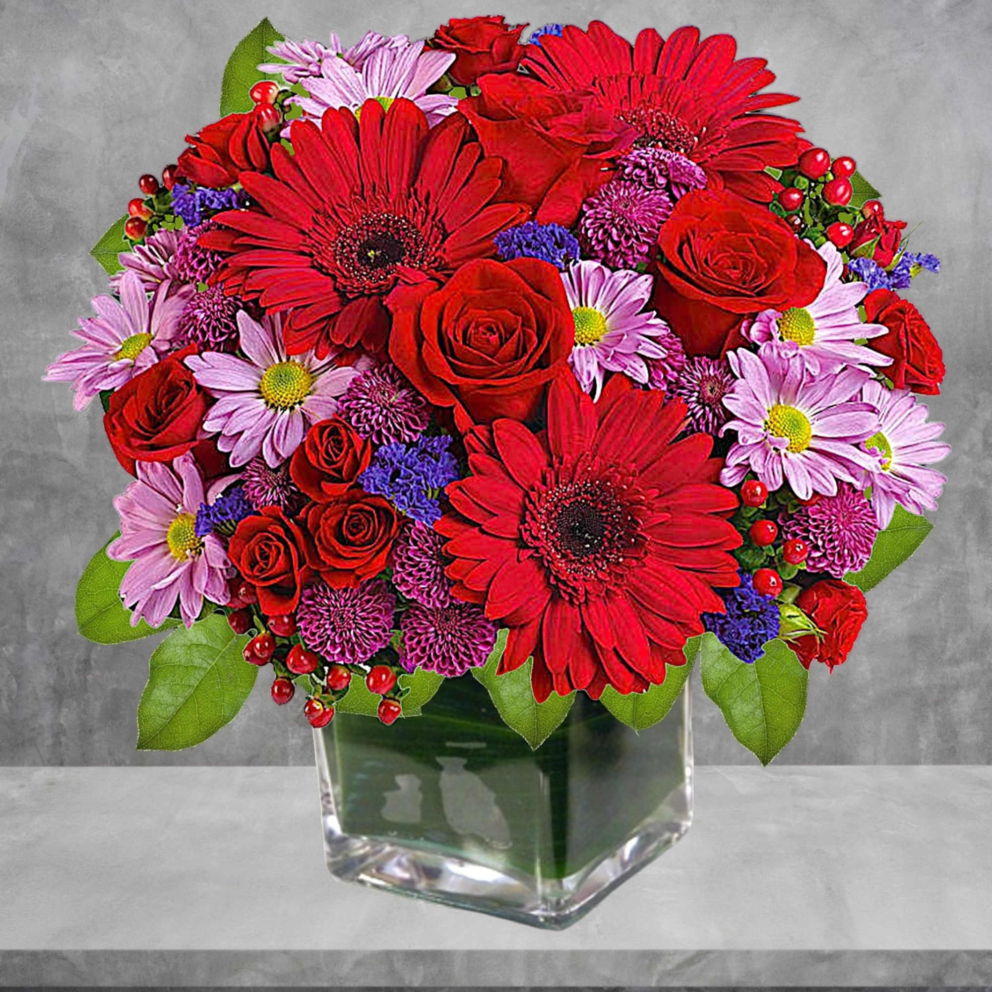 Rich jewel-toned flowers are arranged in a glass cube vase for a