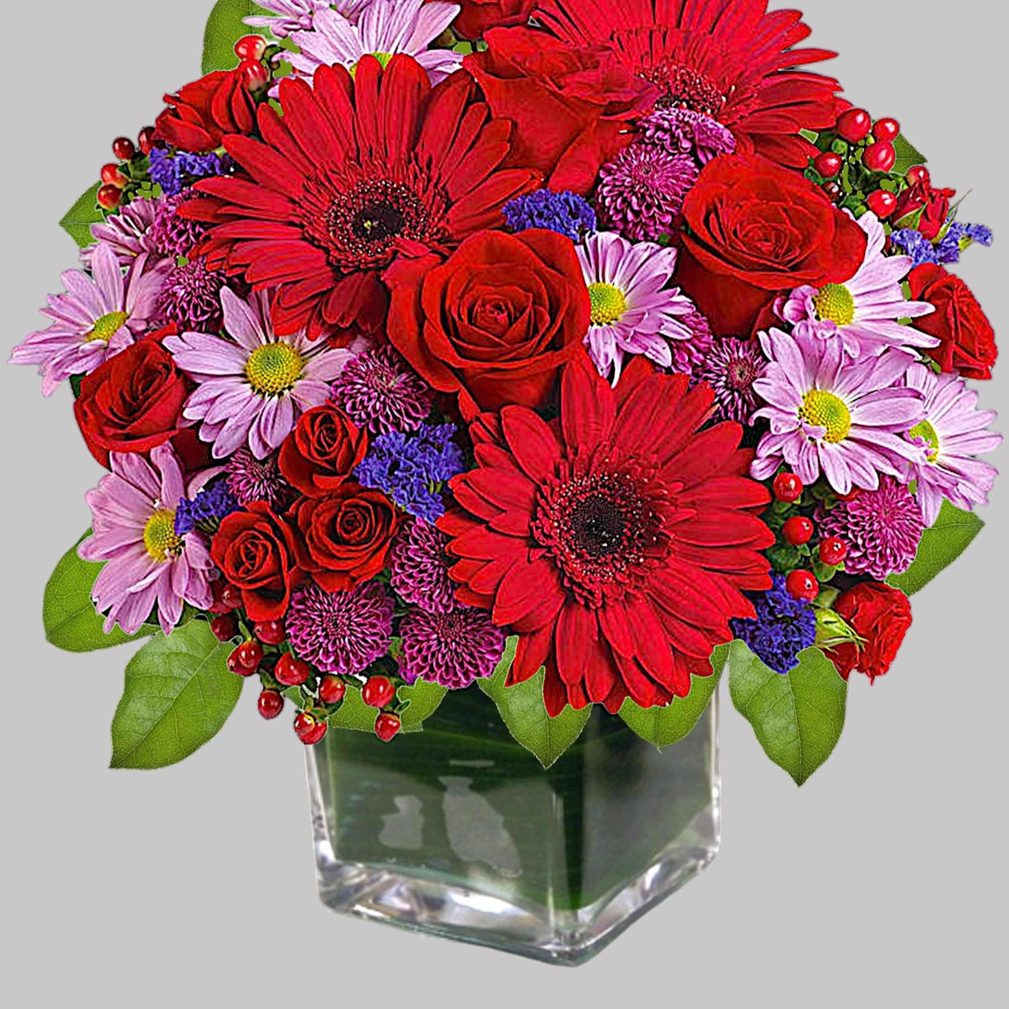 Rich jewel-toned flowers are arranged in a glass cube vase for a