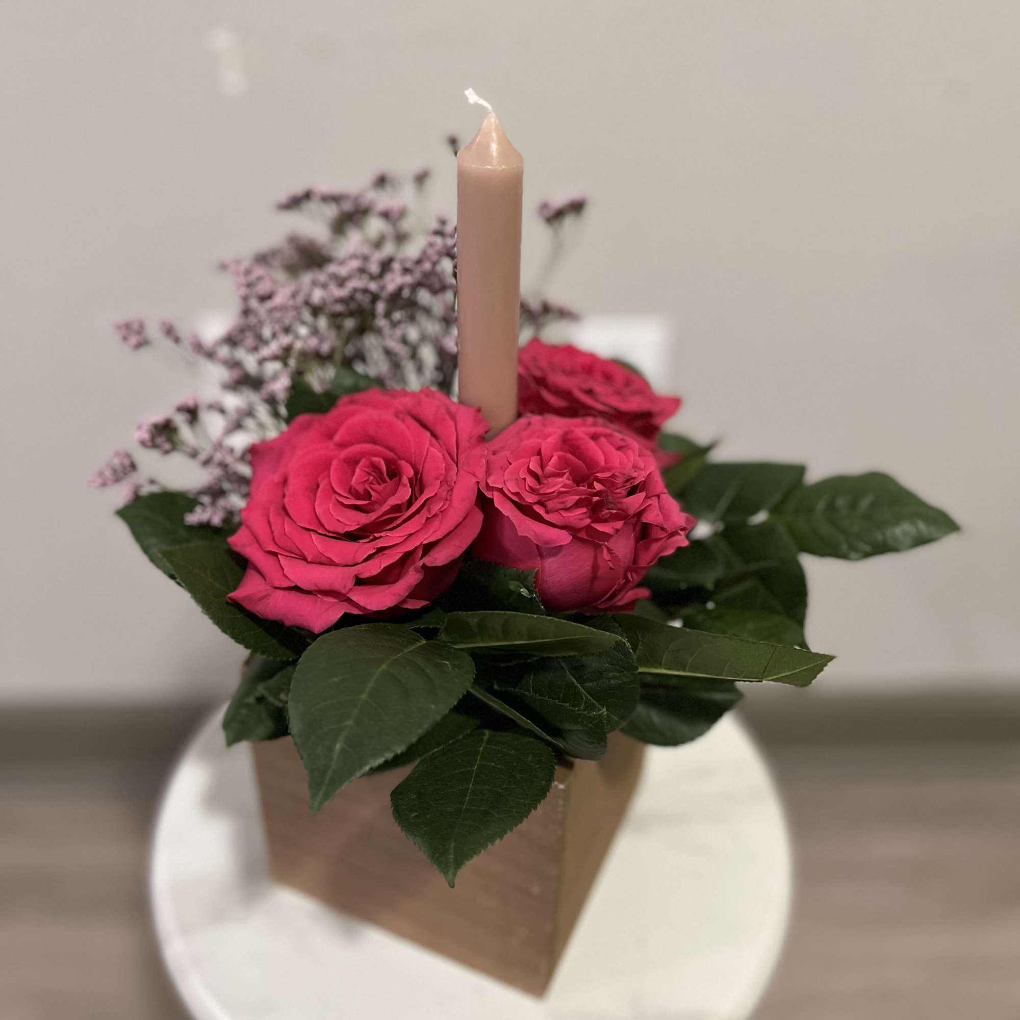 Centerpiece blending warm ambiance. featuring roses nested around a radiant candle. This