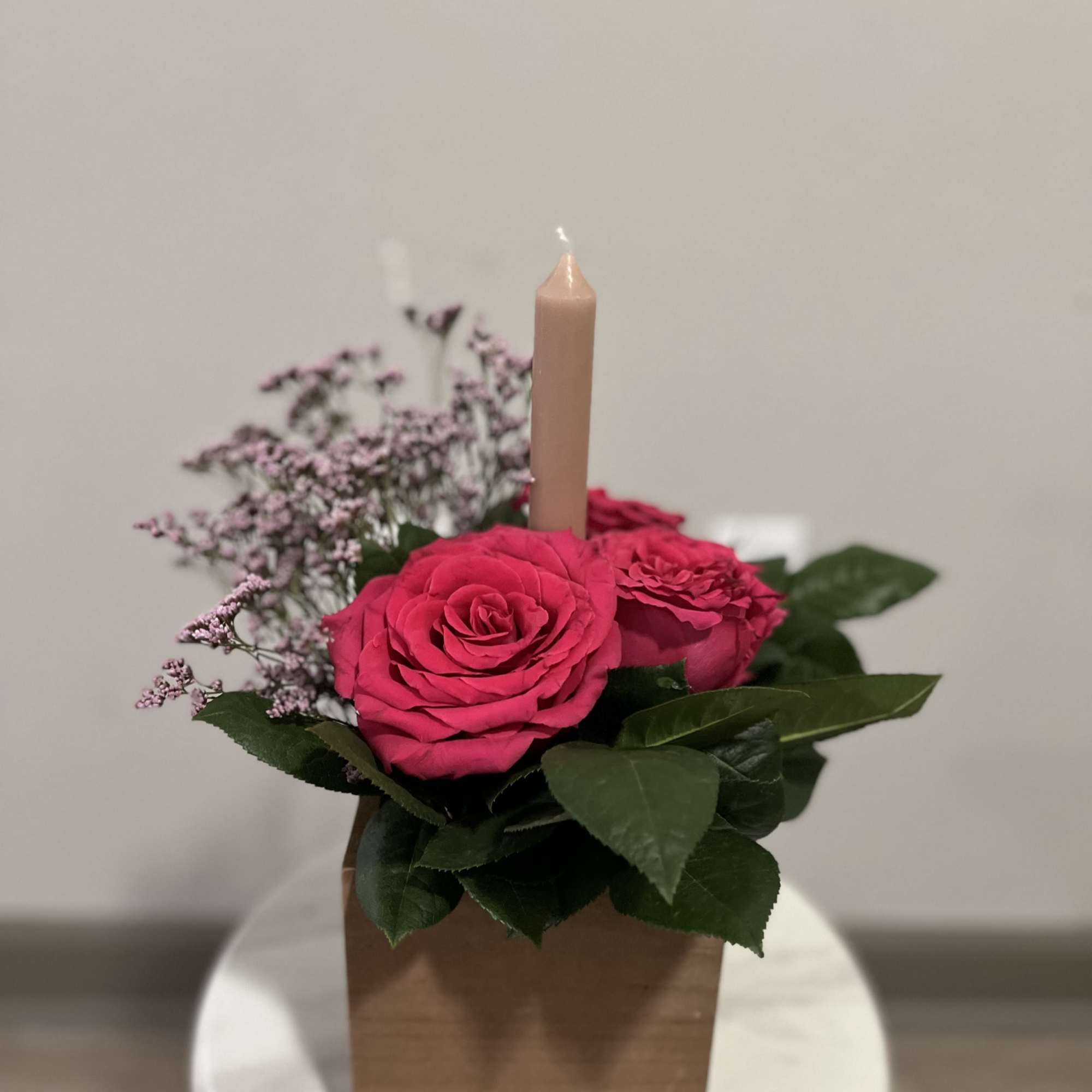 Centerpiece blending warm ambiance. featuring roses nested around a radiant candle. This