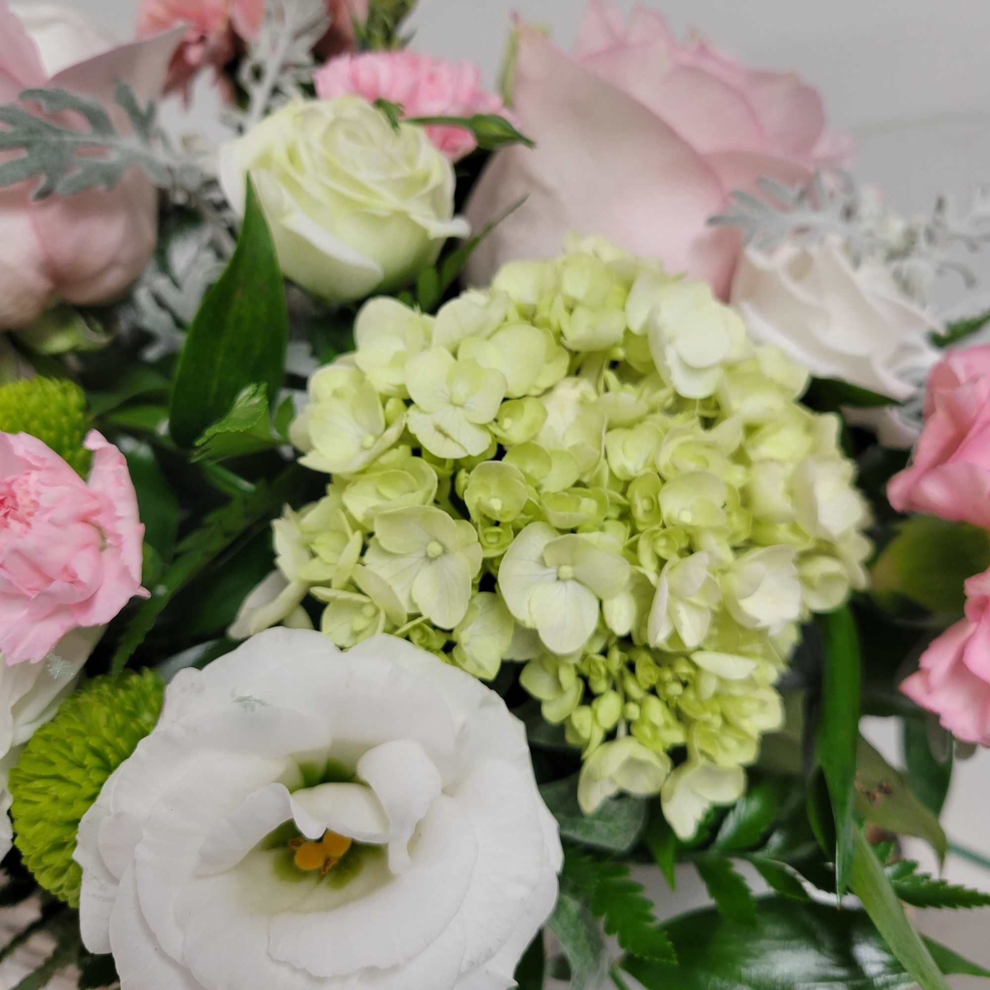 A soft palette of white, pink and green flowers designed in a