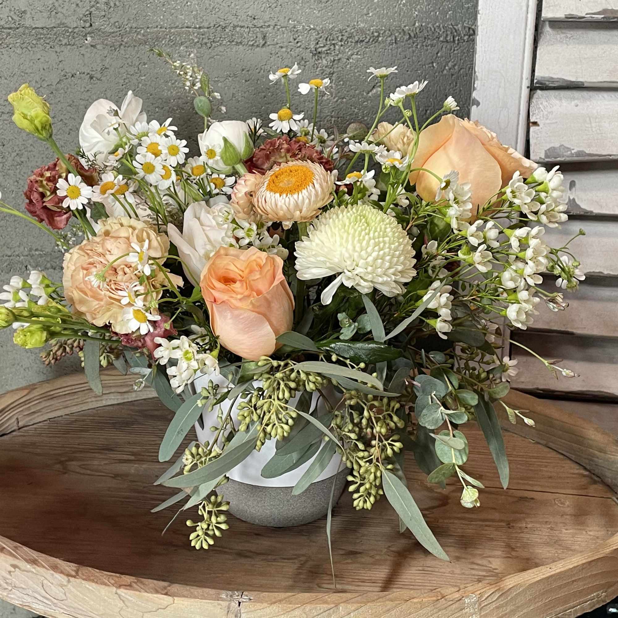 Cozy up with sweet chamomile, waxflower, peach roses, strawflower, and seasonal eucalyptus