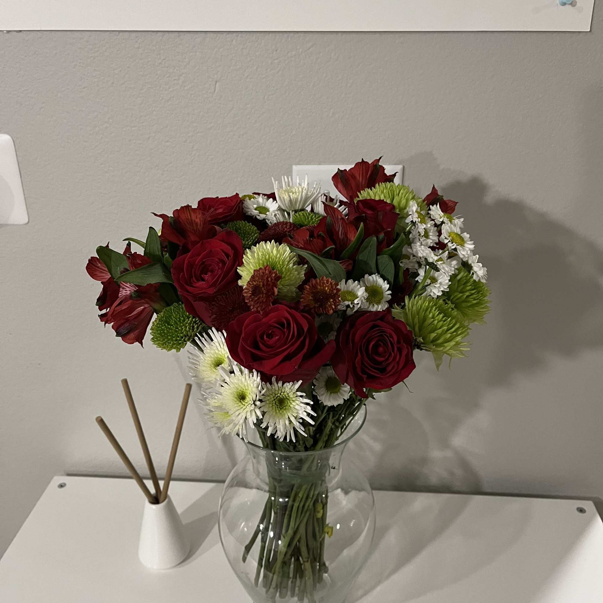 This bouquet features red roses paired with spider chrysanthemums (mums). It is