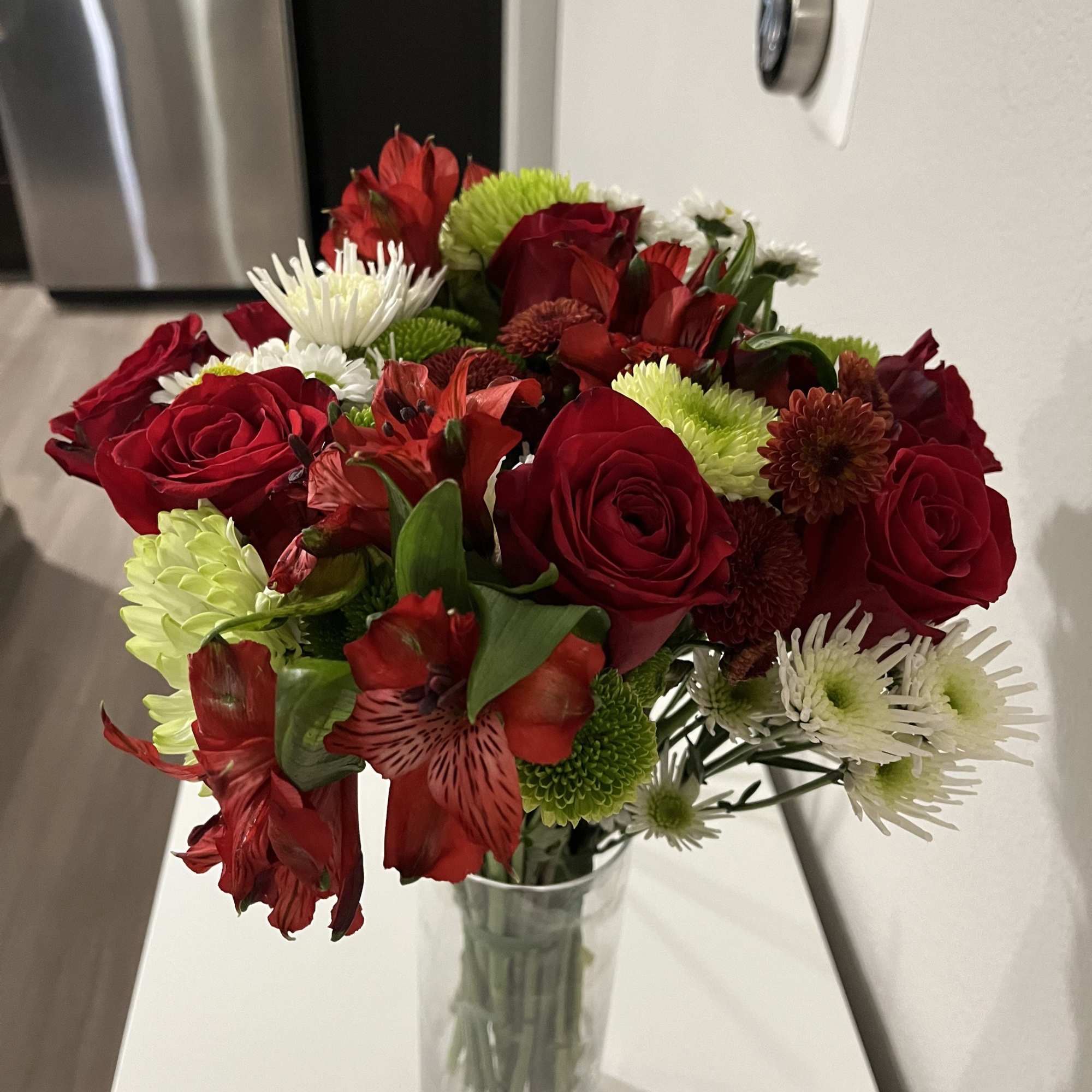 This bouquet features red roses paired with spider chrysanthemums (mums). It is