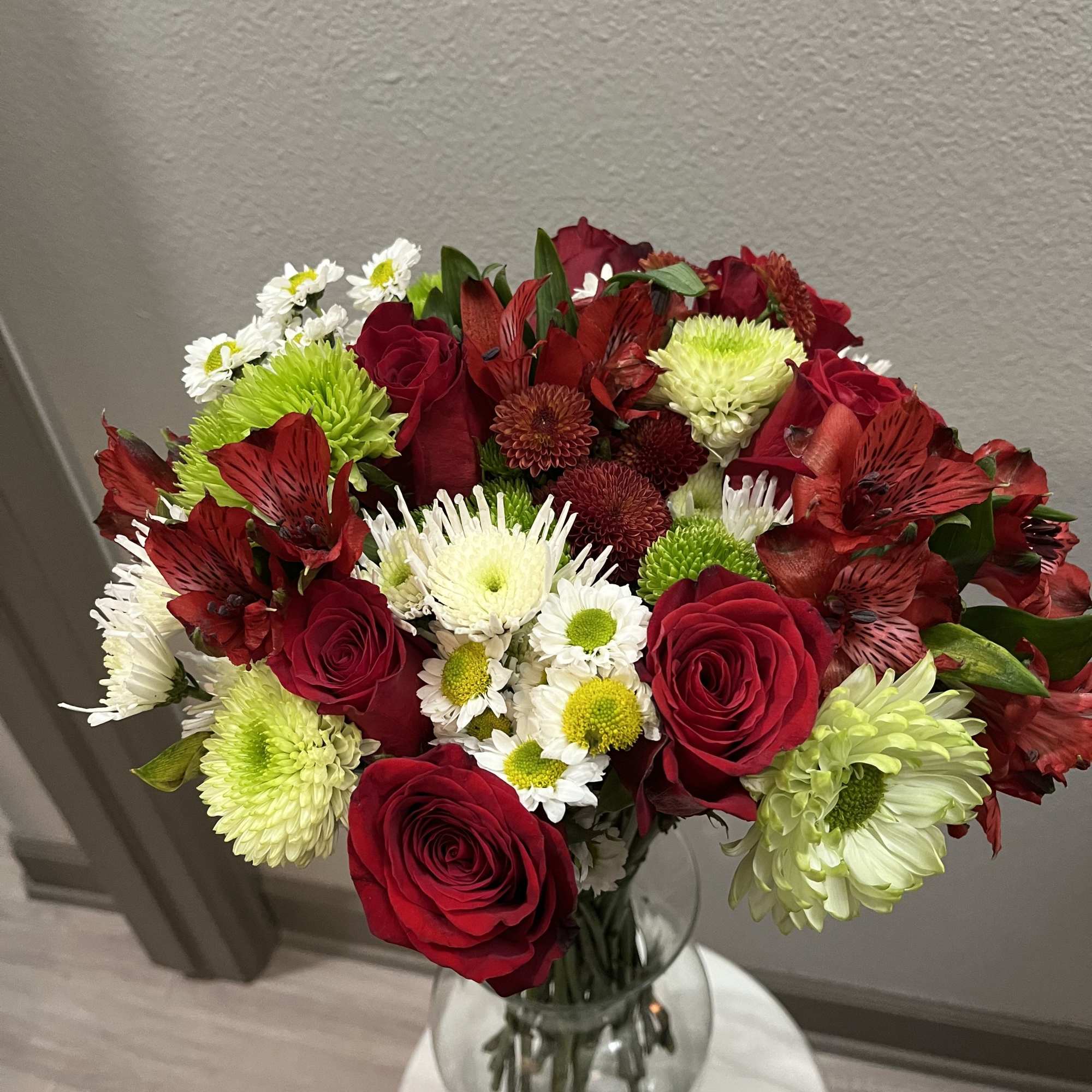 This bouquet features red roses paired with spider chrysanthemums (mums). It is