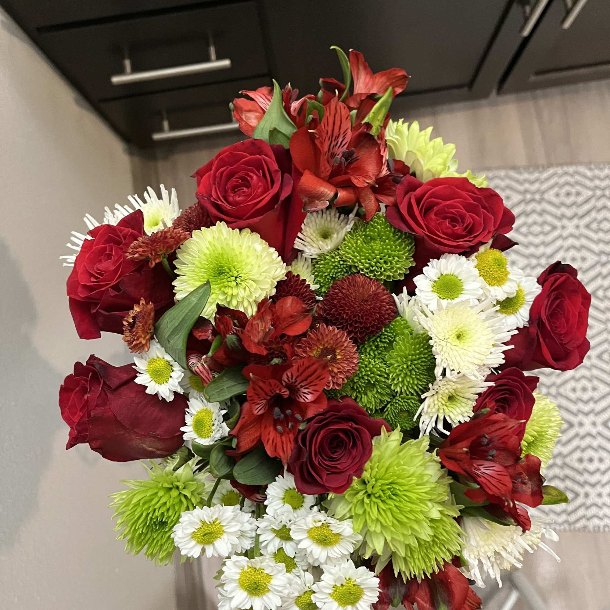 This bouquet features red roses paired with spider chrysanthemums (mums). It is