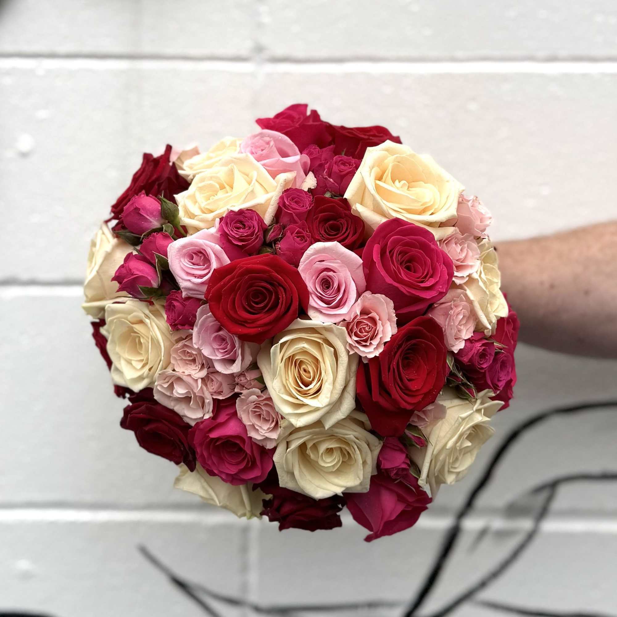 A timeless arrangement of delicate pink, red and white roses, this bouquet