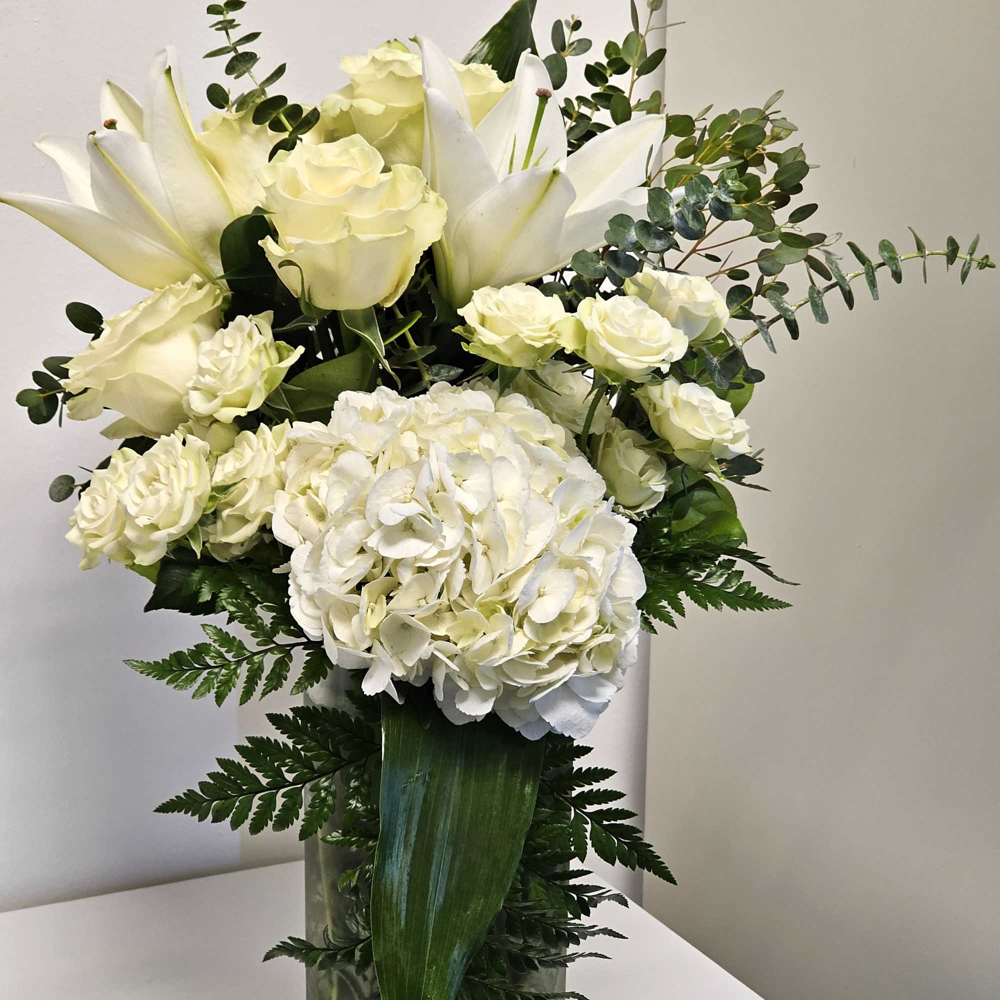

This exquisite all-white arrangement embodies grace and sophistication. At the heart of