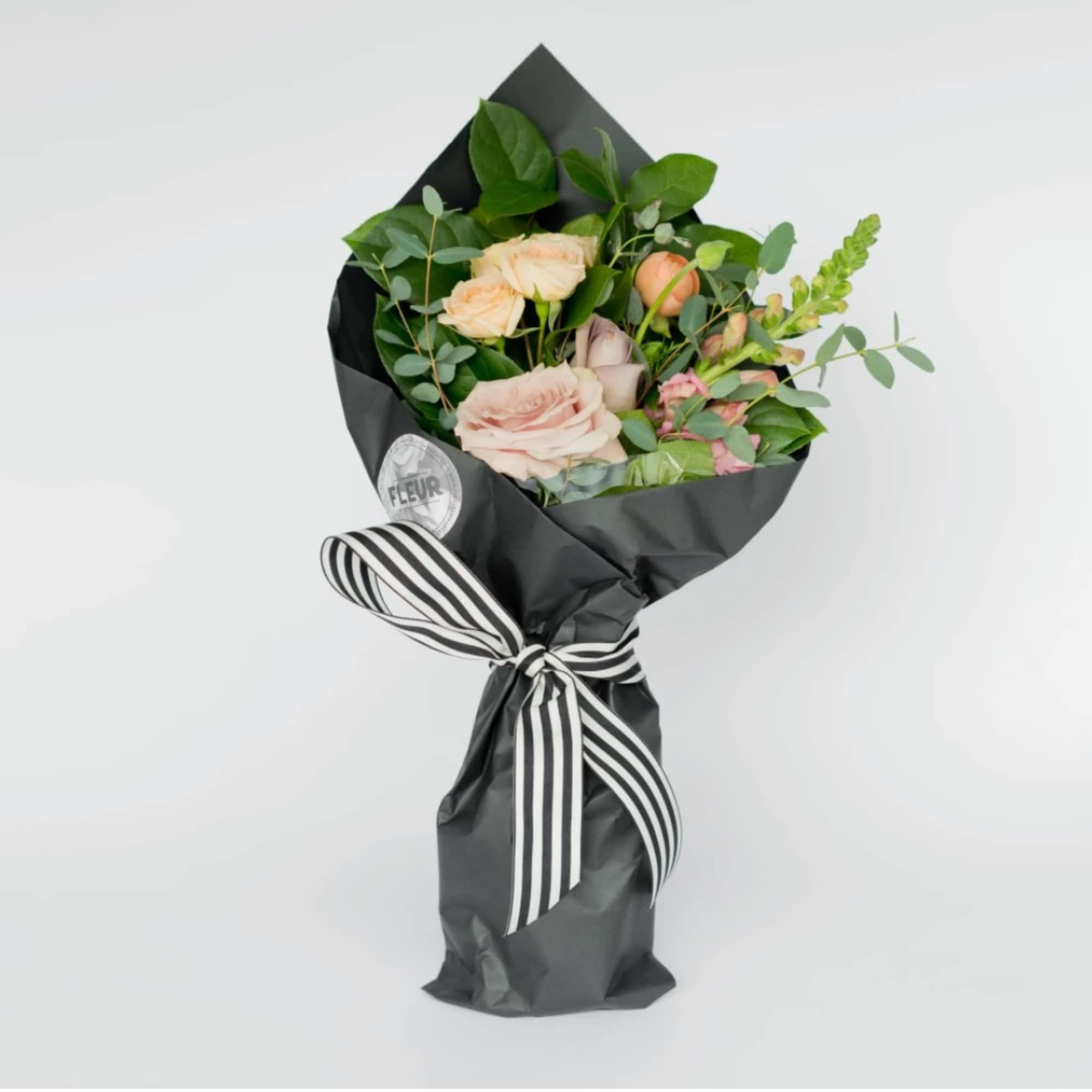 Seasonal blooms and foliage packaged in a classic black market paper. Includes
