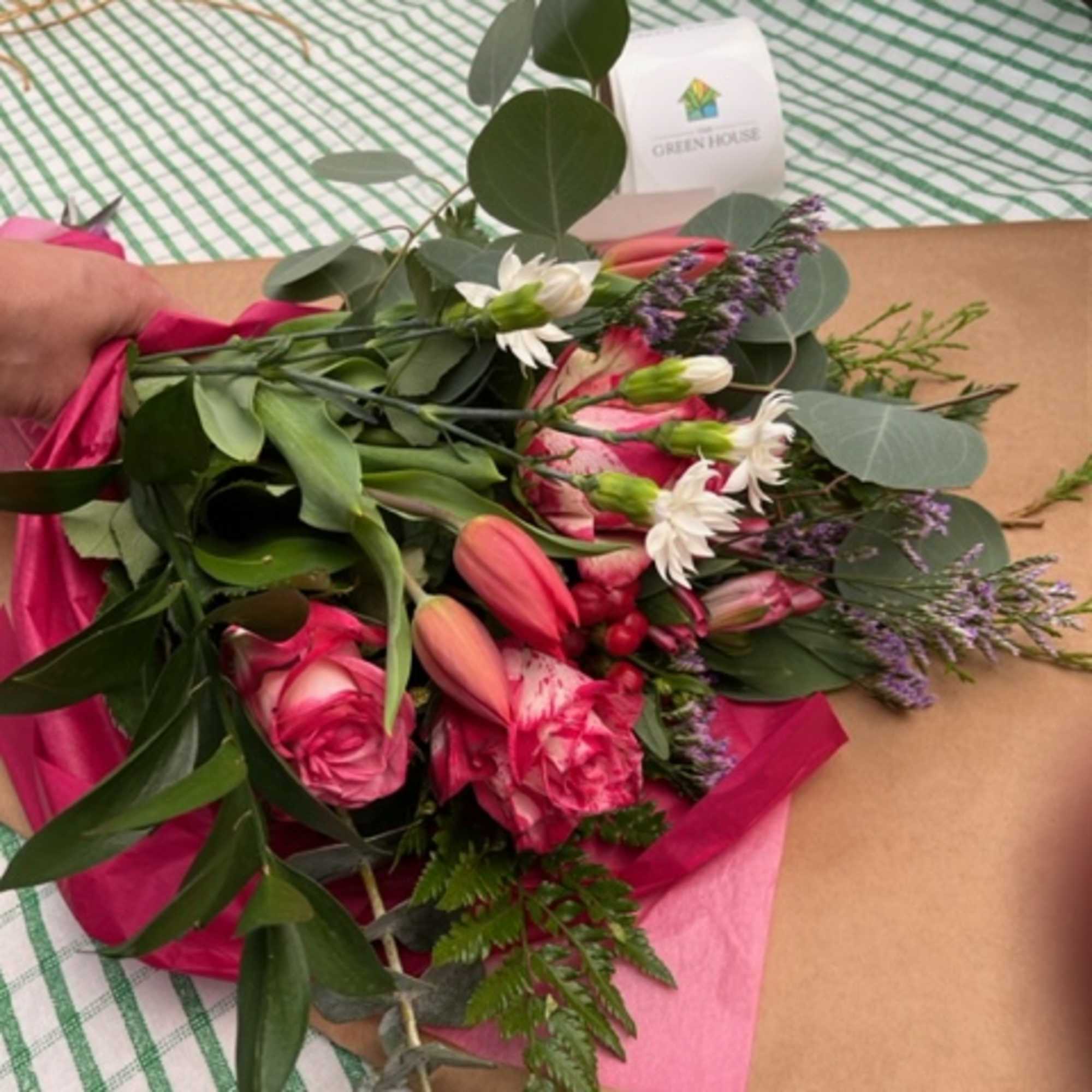 A beautiful hand wrapped bouquet of mixed blooms and greenery