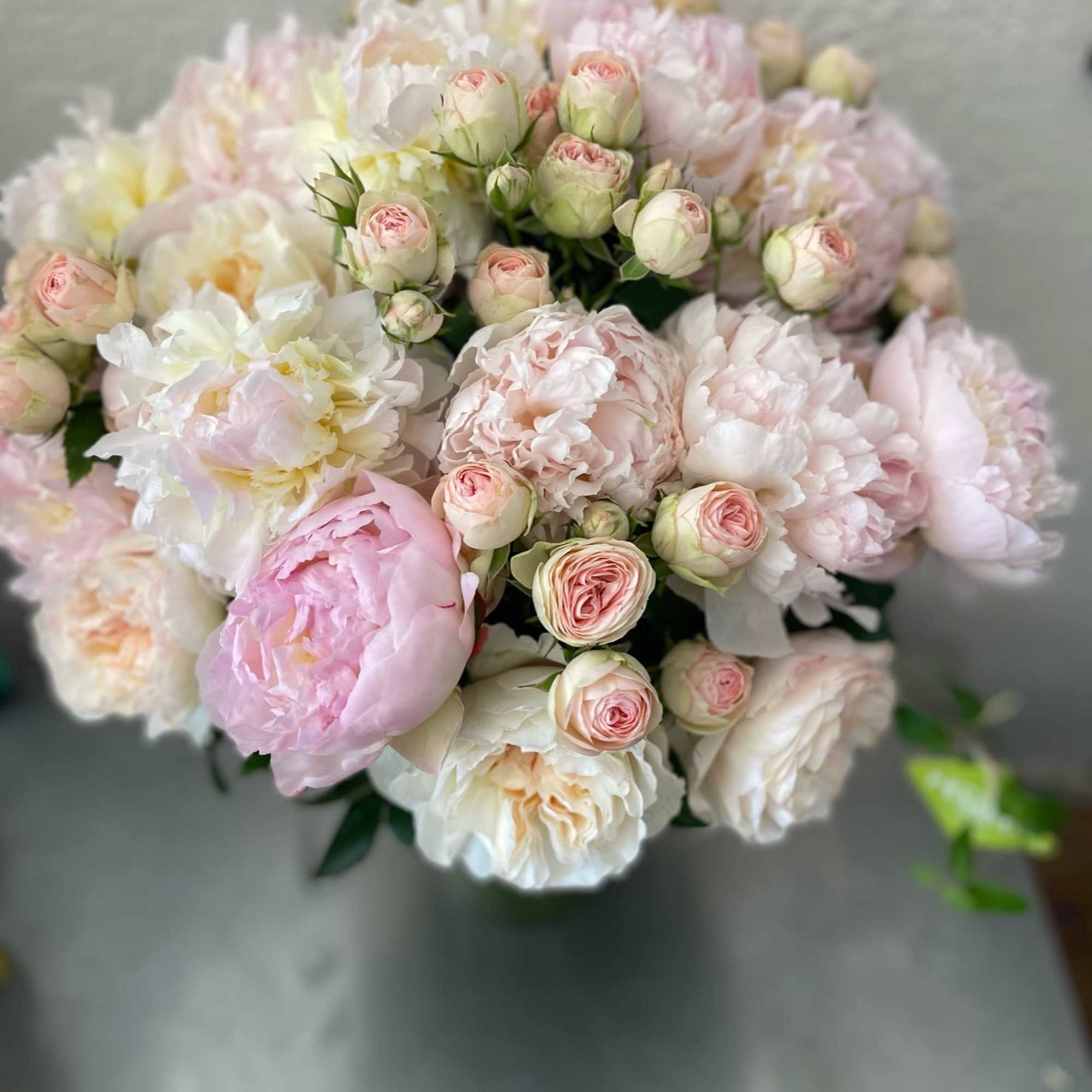 Tall leaf lined vase with peonies, garden roses, spray roses and mini