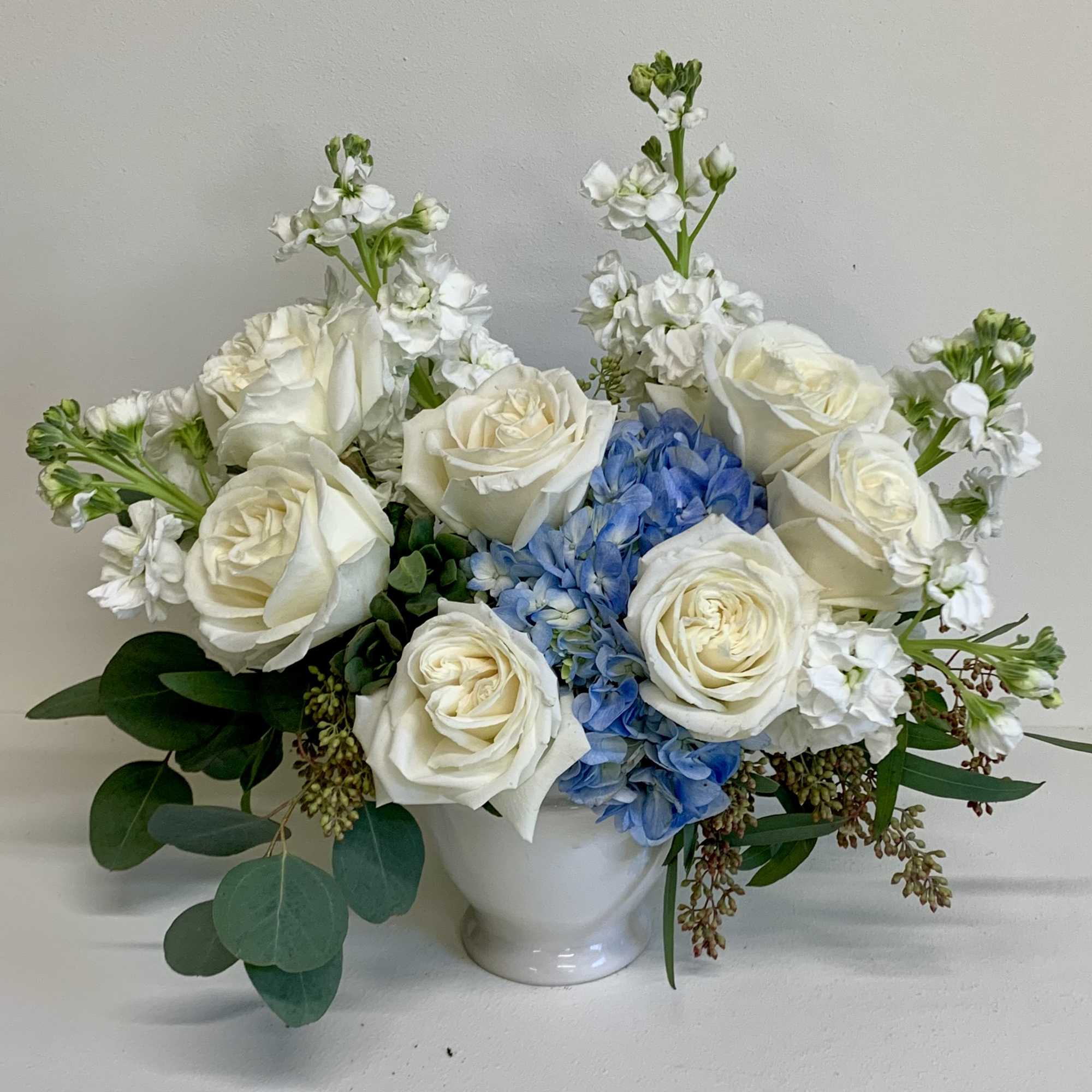 A soft, comforting mix of white roses, white stock and a blue