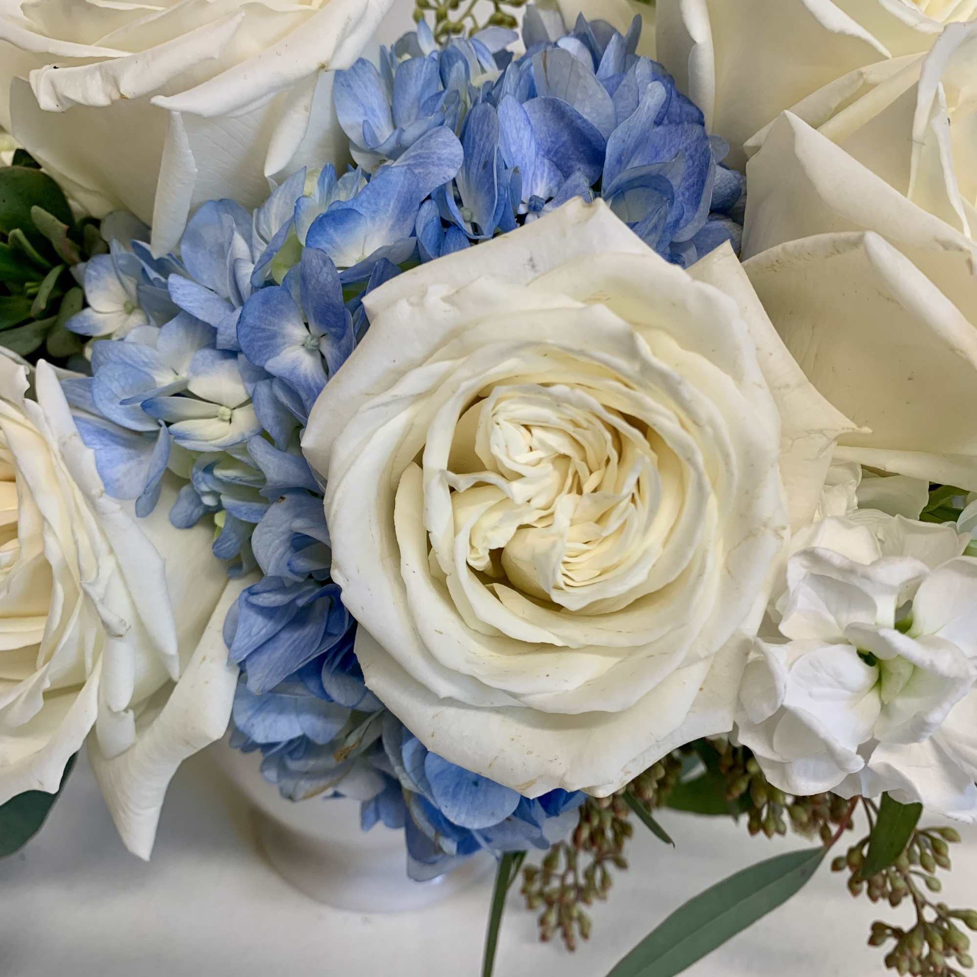 A soft, comforting mix of white roses, white stock and a blue