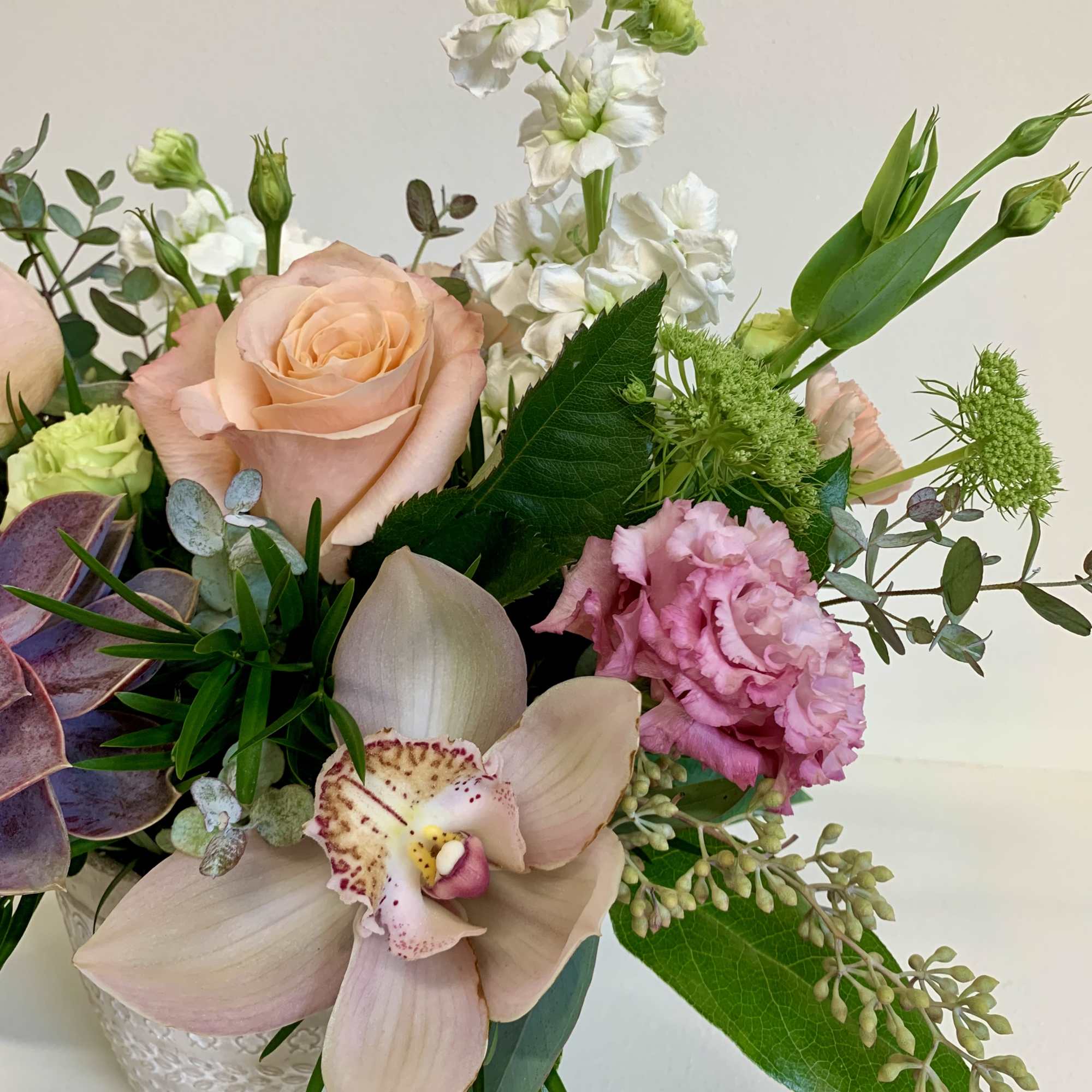 A desert esque arrangement with shimmer roses, white stock, peach carnations, and