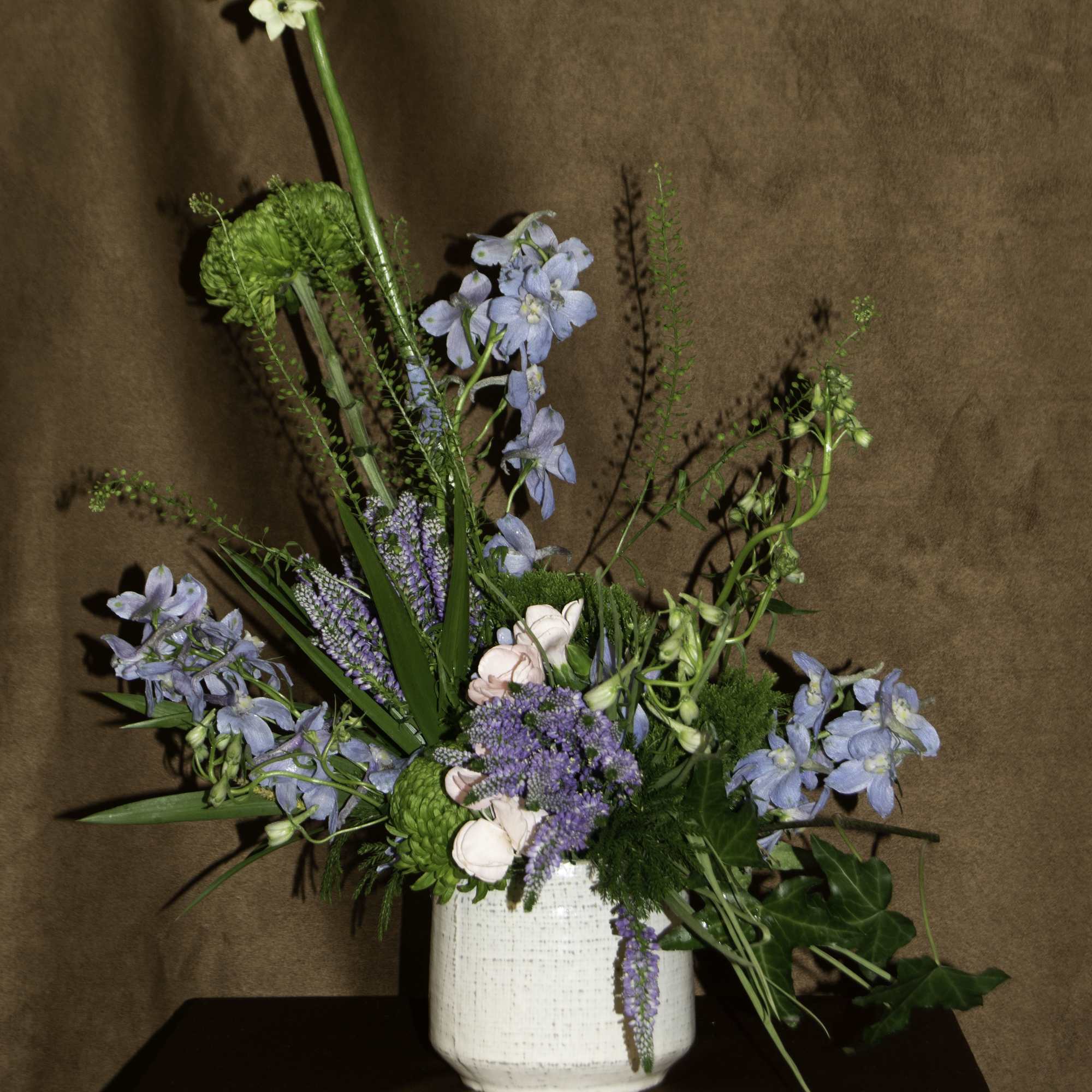 The &quot;Dagon&quot; floral arrangement features a mix of green chrysanthemums, blue delphiniums