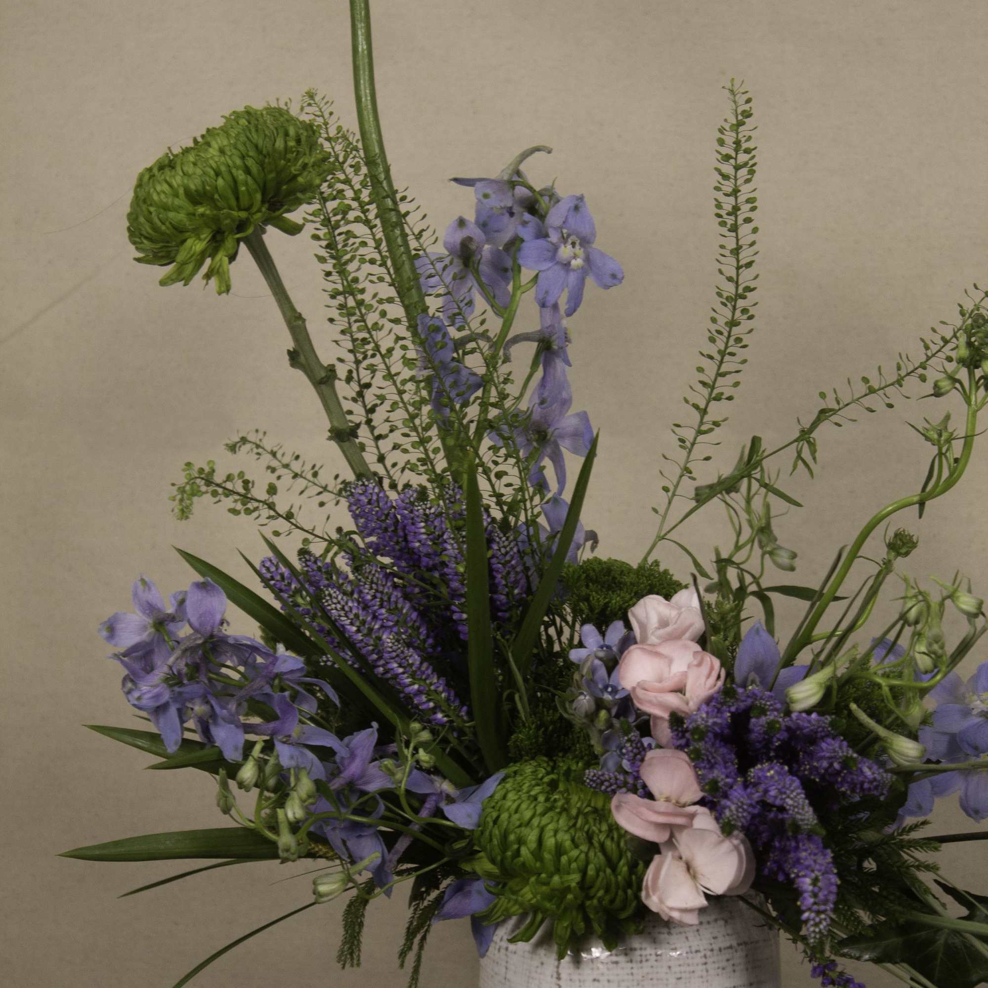 The &quot;Dagon&quot; floral arrangement features a mix of green chrysanthemums, blue delphiniums