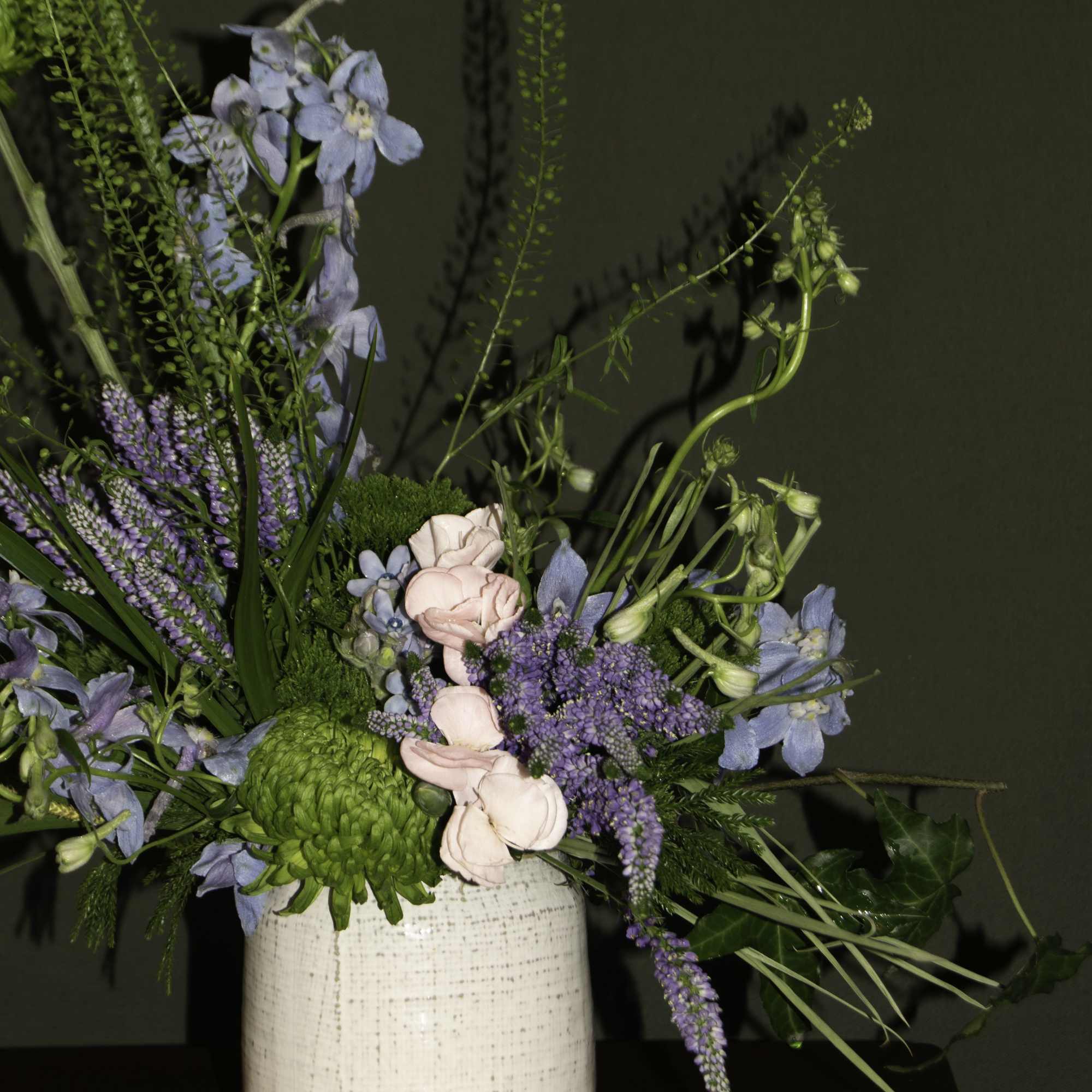 The &quot;Dagon&quot; floral arrangement features a mix of green chrysanthemums, blue delphiniums