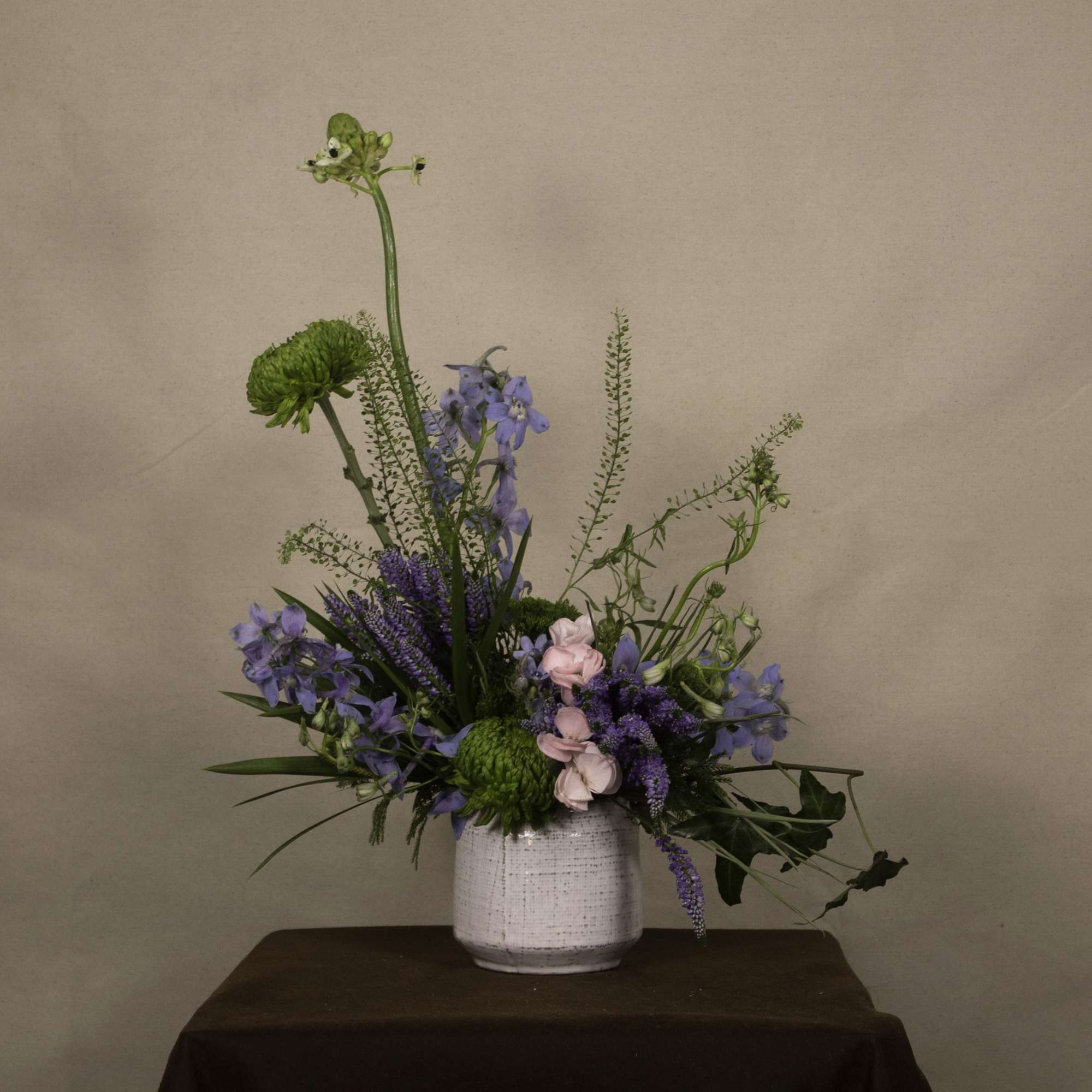 The &quot;Dagon&quot; floral arrangement features a mix of green chrysanthemums, blue delphiniums
