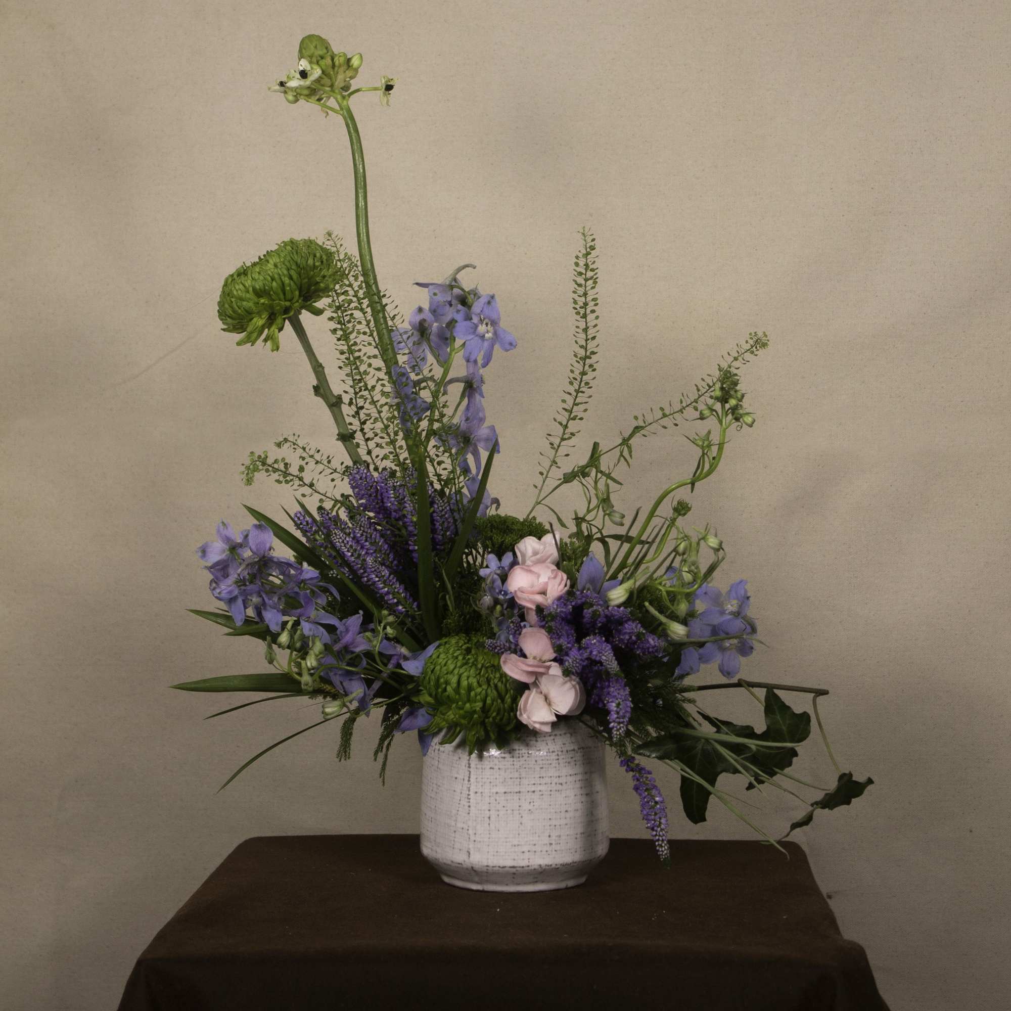 The &quot;Dagon&quot; floral arrangement features a mix of green chrysanthemums, blue delphiniums