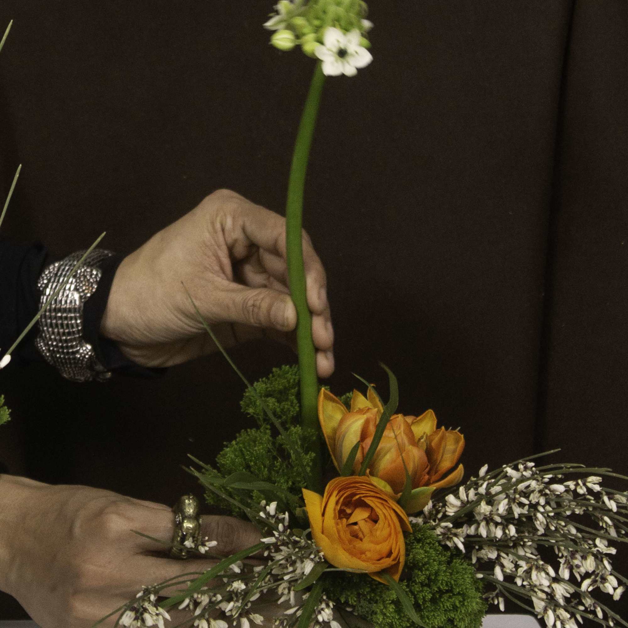 Featuring vibrant orange ranunculus paired with delicate white star-shaped flowers and soft