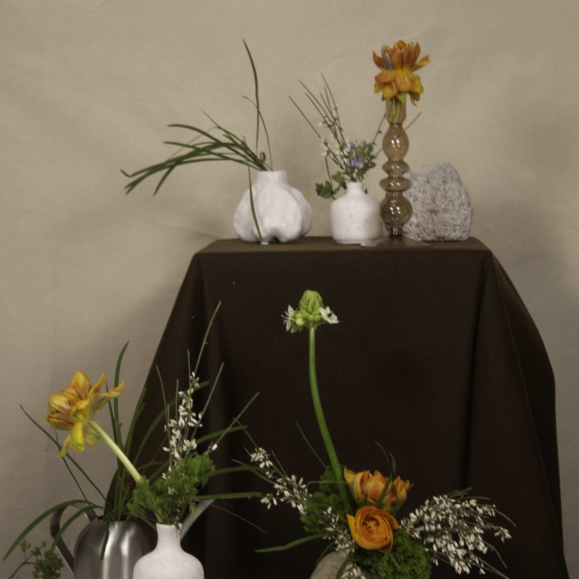 Featuring vibrant orange ranunculus paired with delicate white star-shaped flowers and soft