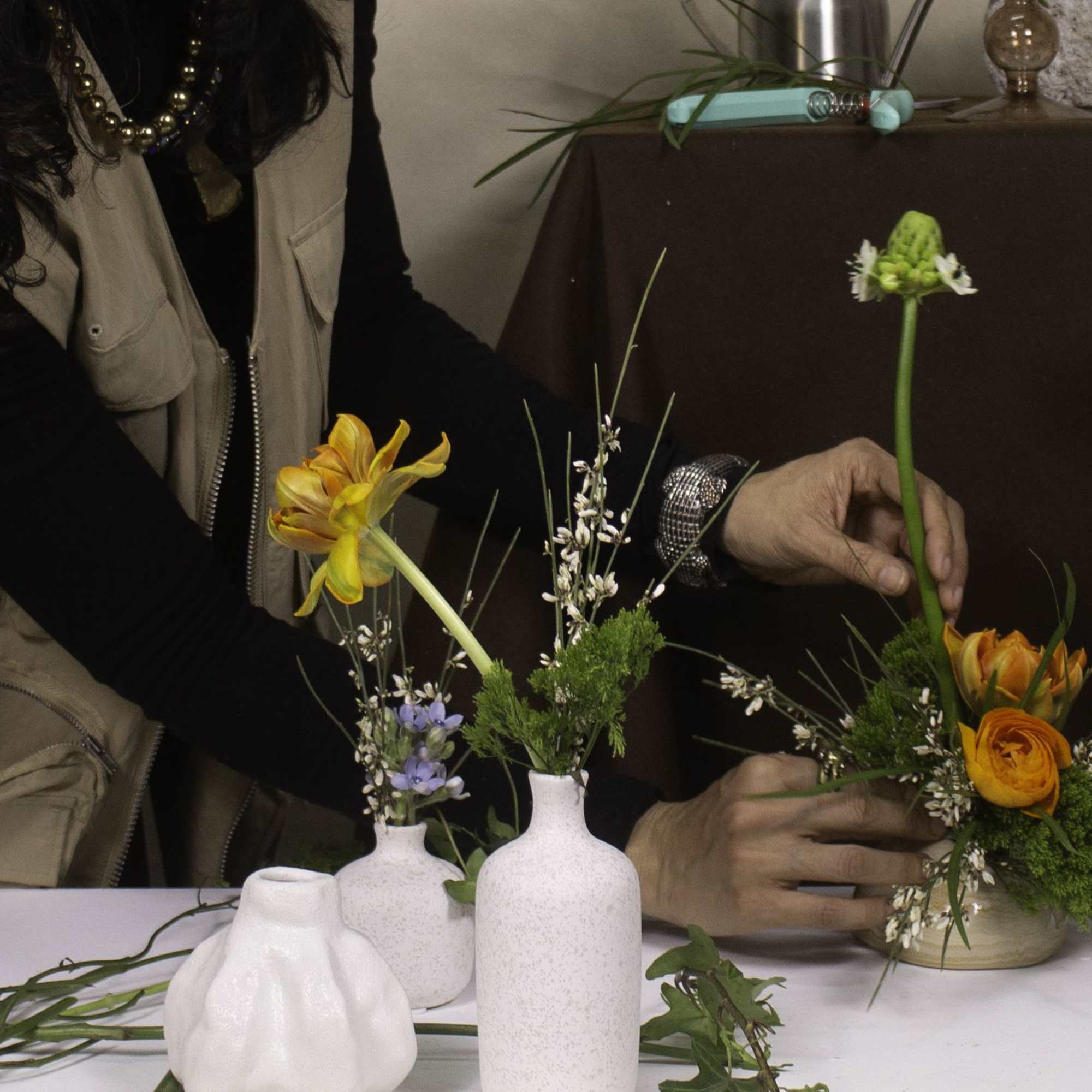 Featuring vibrant orange ranunculus paired with delicate white star-shaped flowers and soft