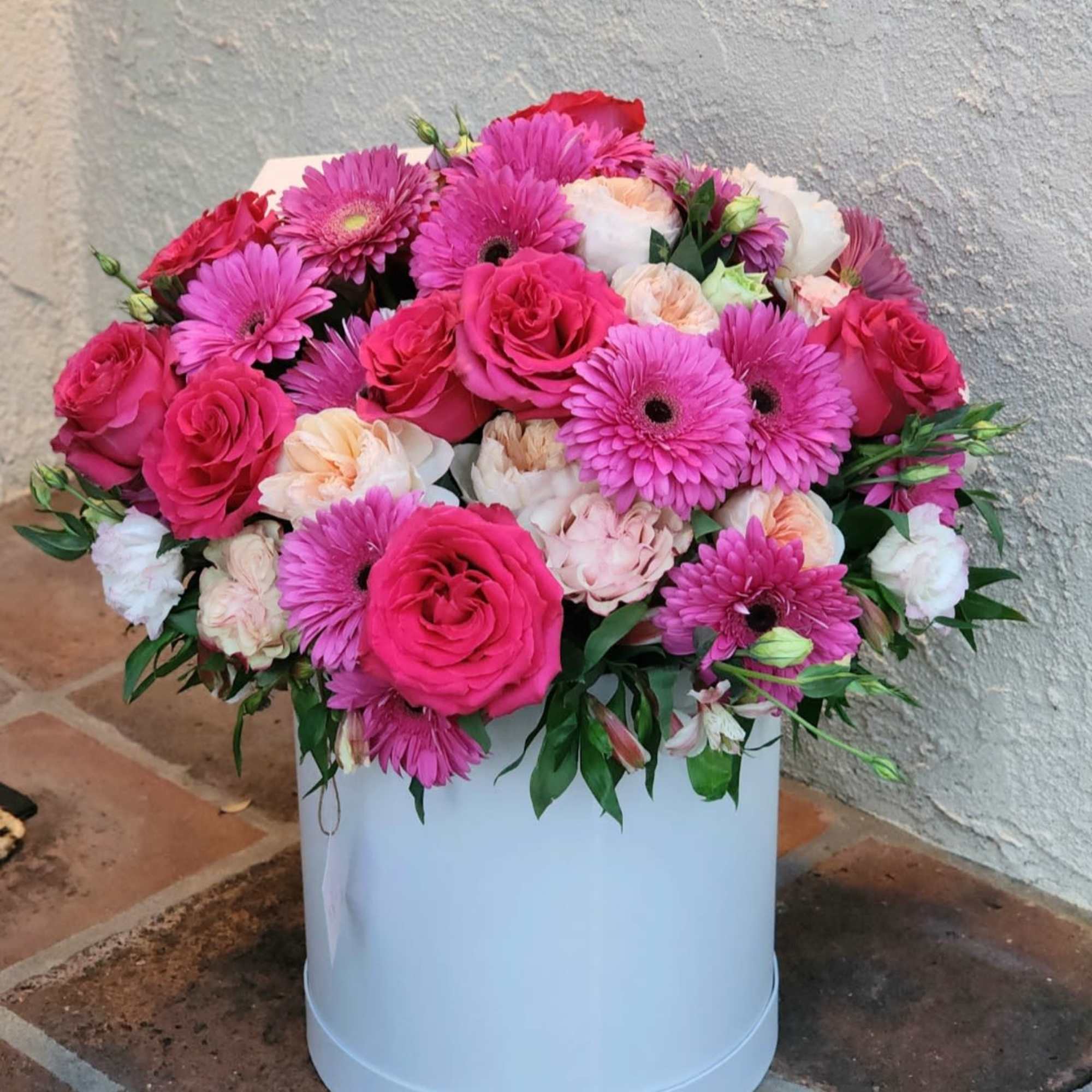 Vibrant floral arrangement, beautifully displayed in a white hatbox. This stunning mix