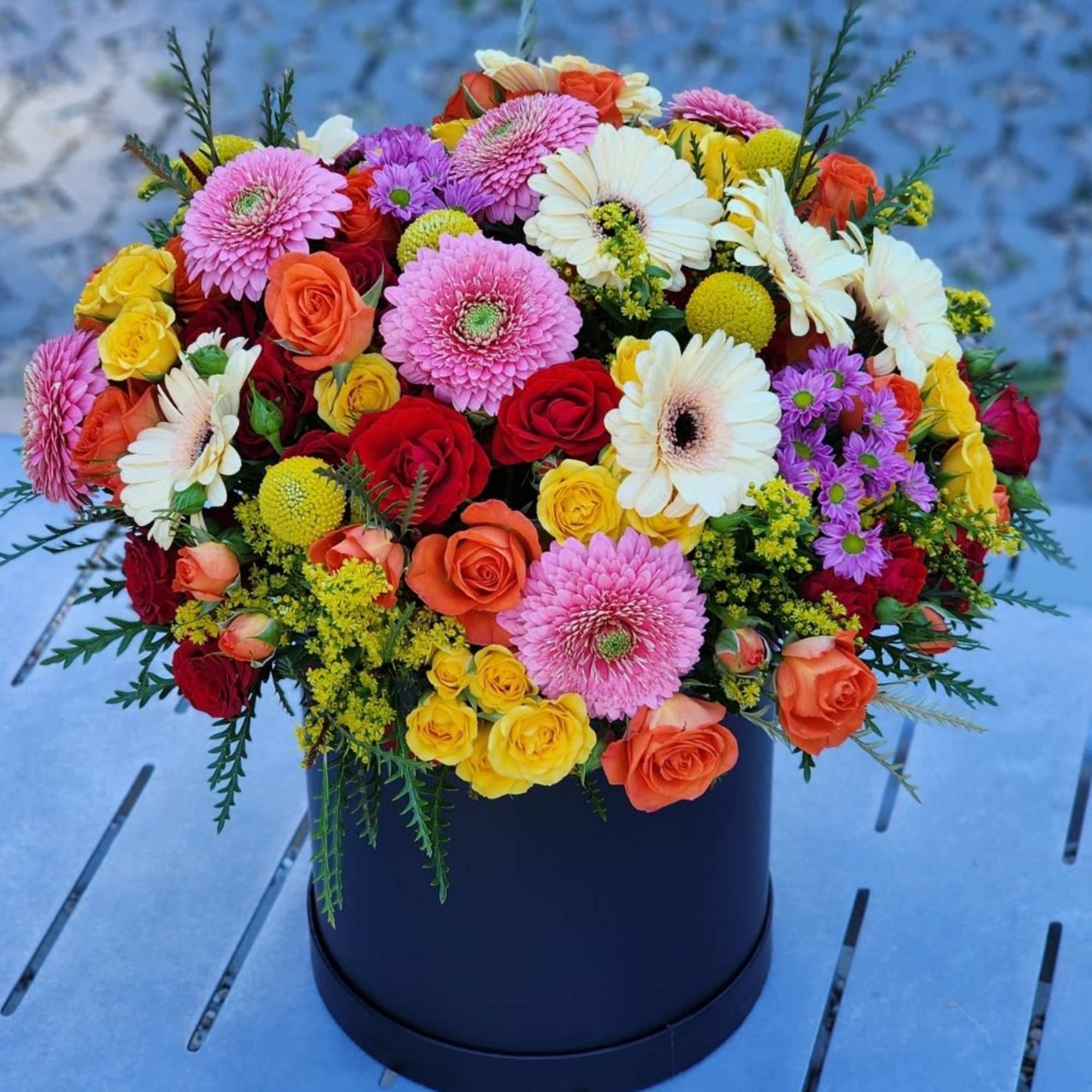 This floral arrangement showcases a vibrant mix of roses, gerberas, presented in