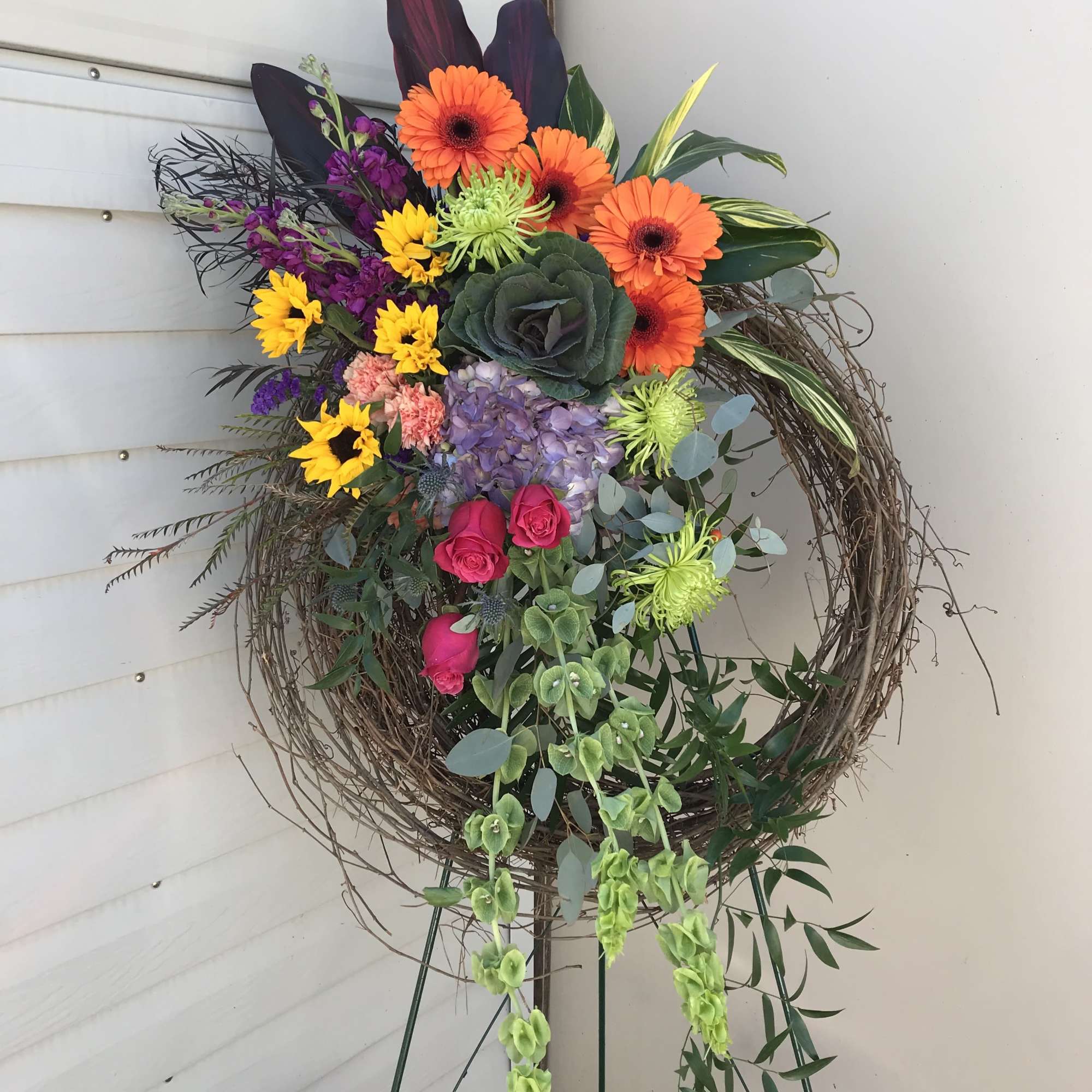 A grapevine wreath with a beautiful array of bright, bold, flowers. The