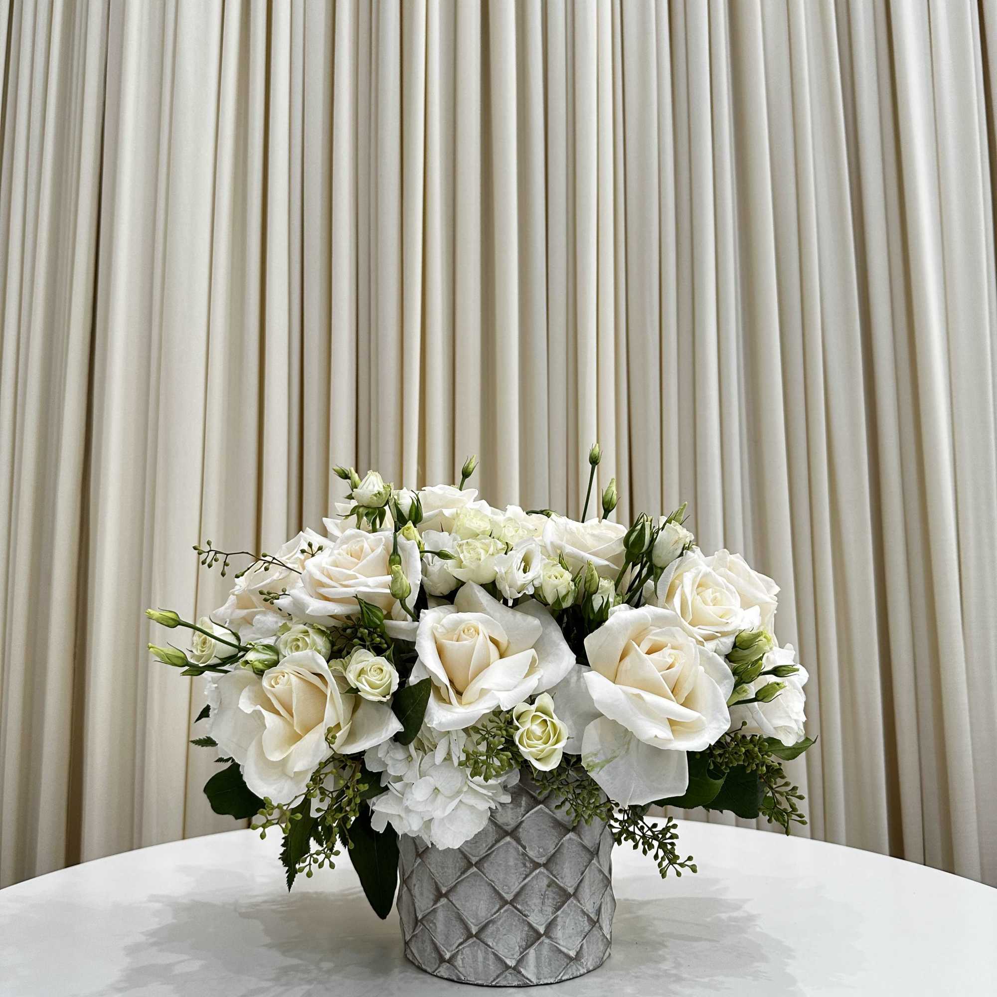 This elegant sympathy arrangement features a stunning white flower arrangement delicately arranged