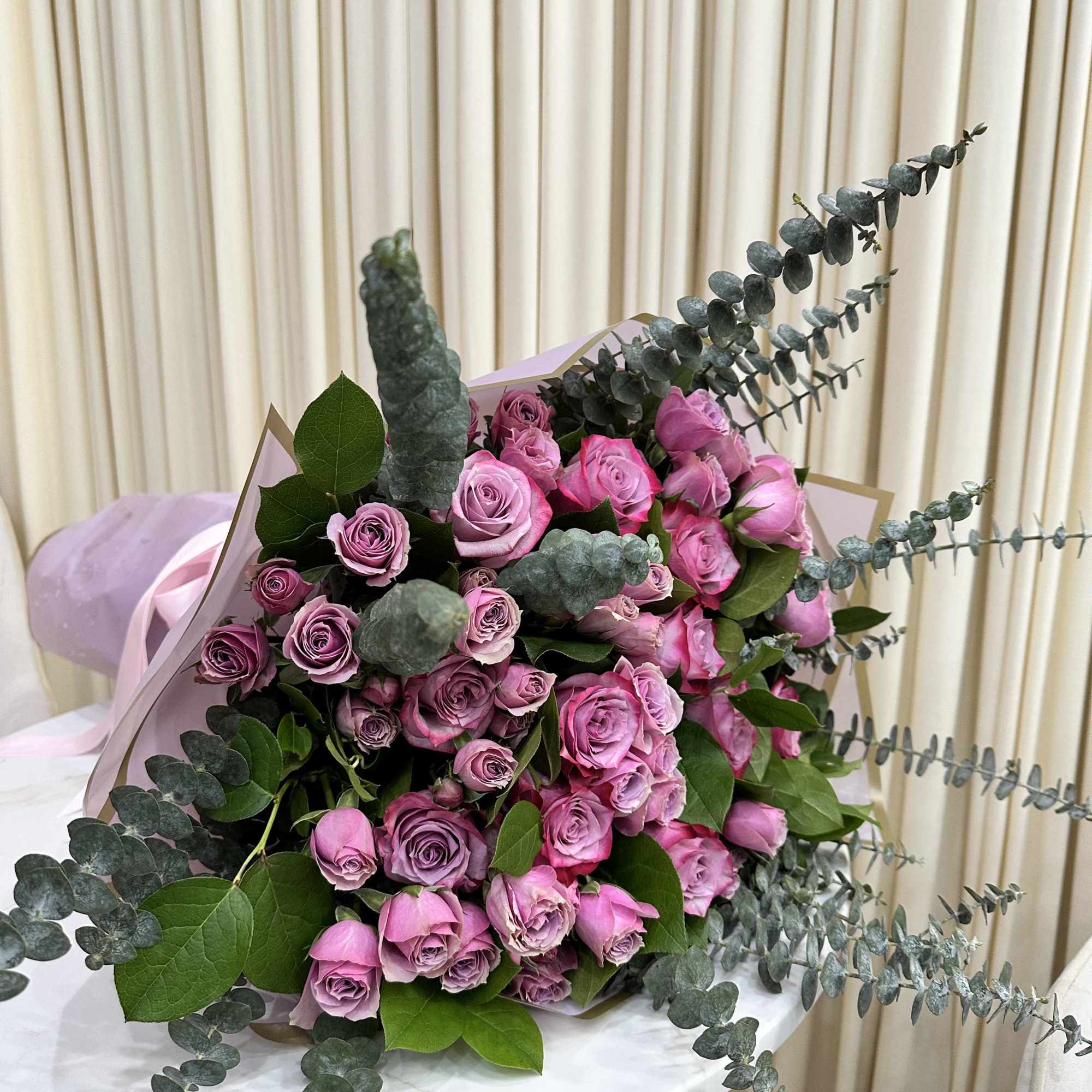 This whimsical bouquet features a cascade of purple roses, baby purple roses
