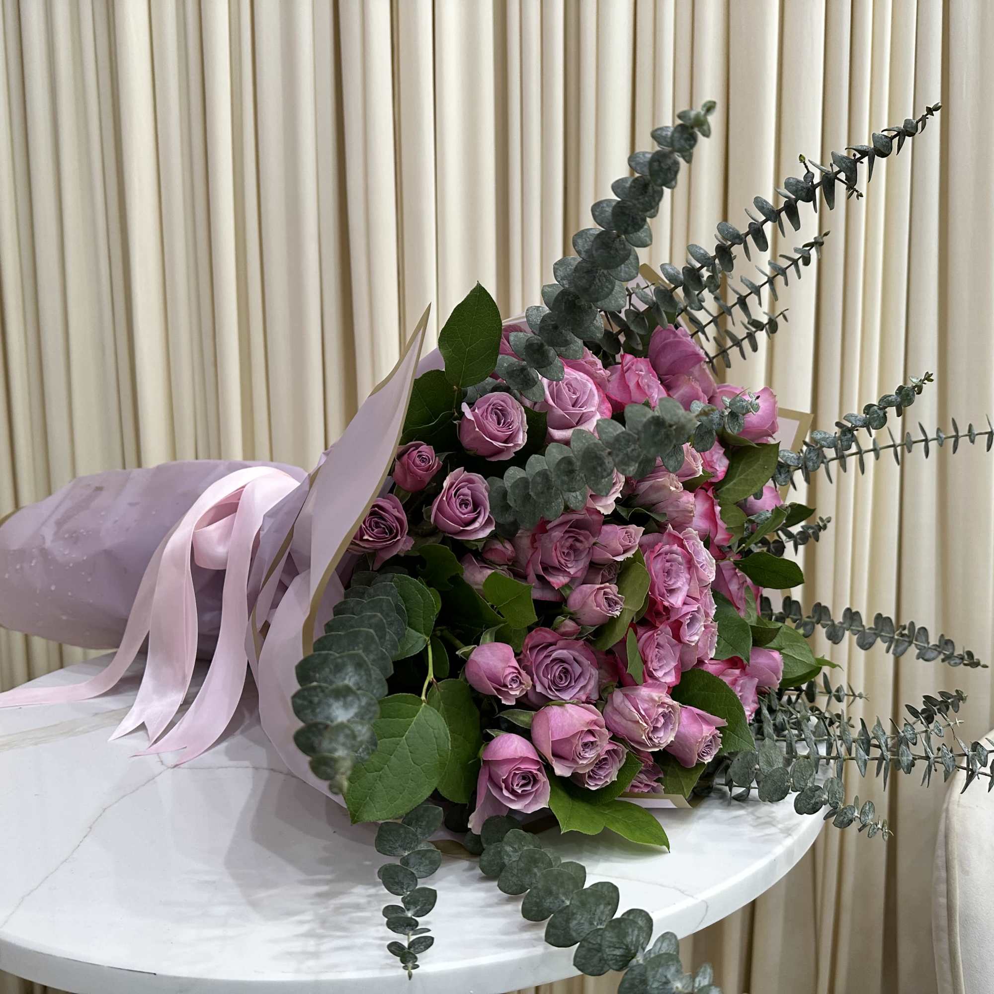 This whimsical bouquet features a cascade of purple roses, baby purple roses