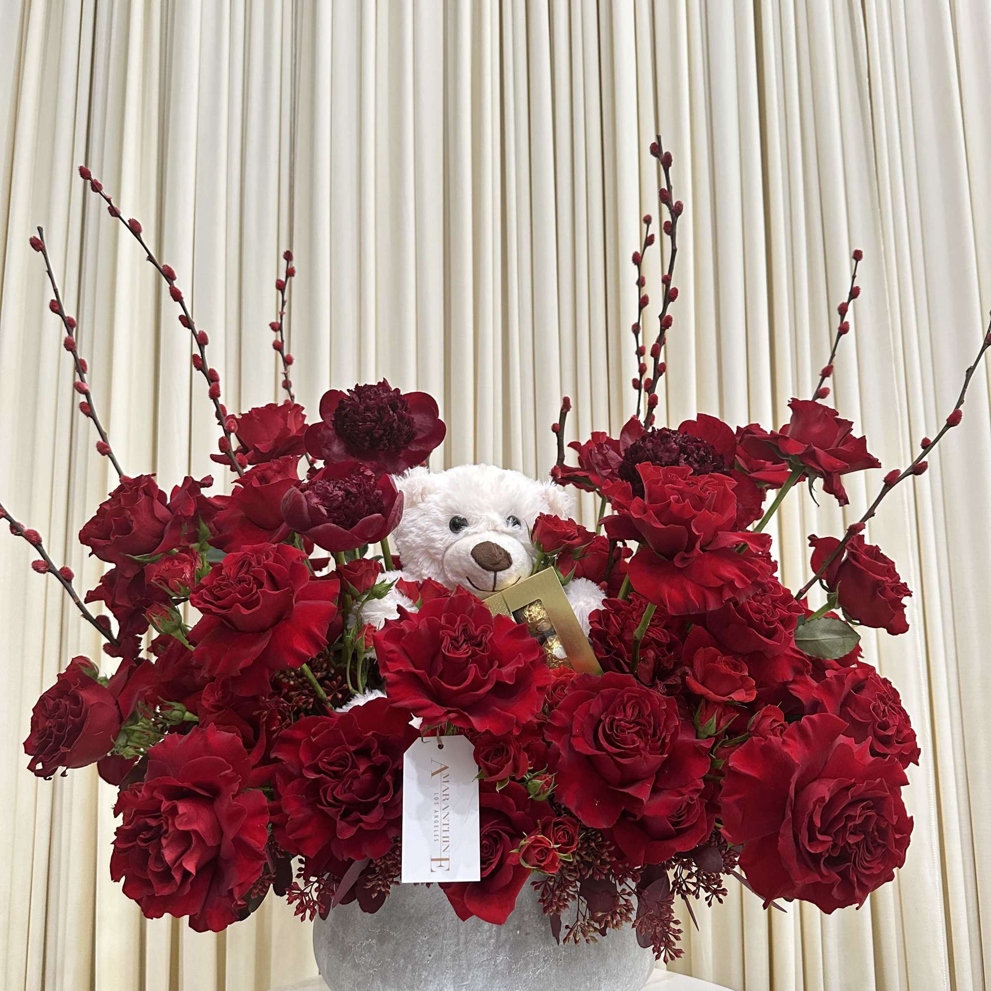 This delightful arrangement features a cuddly white teddy bear nestled amidst a