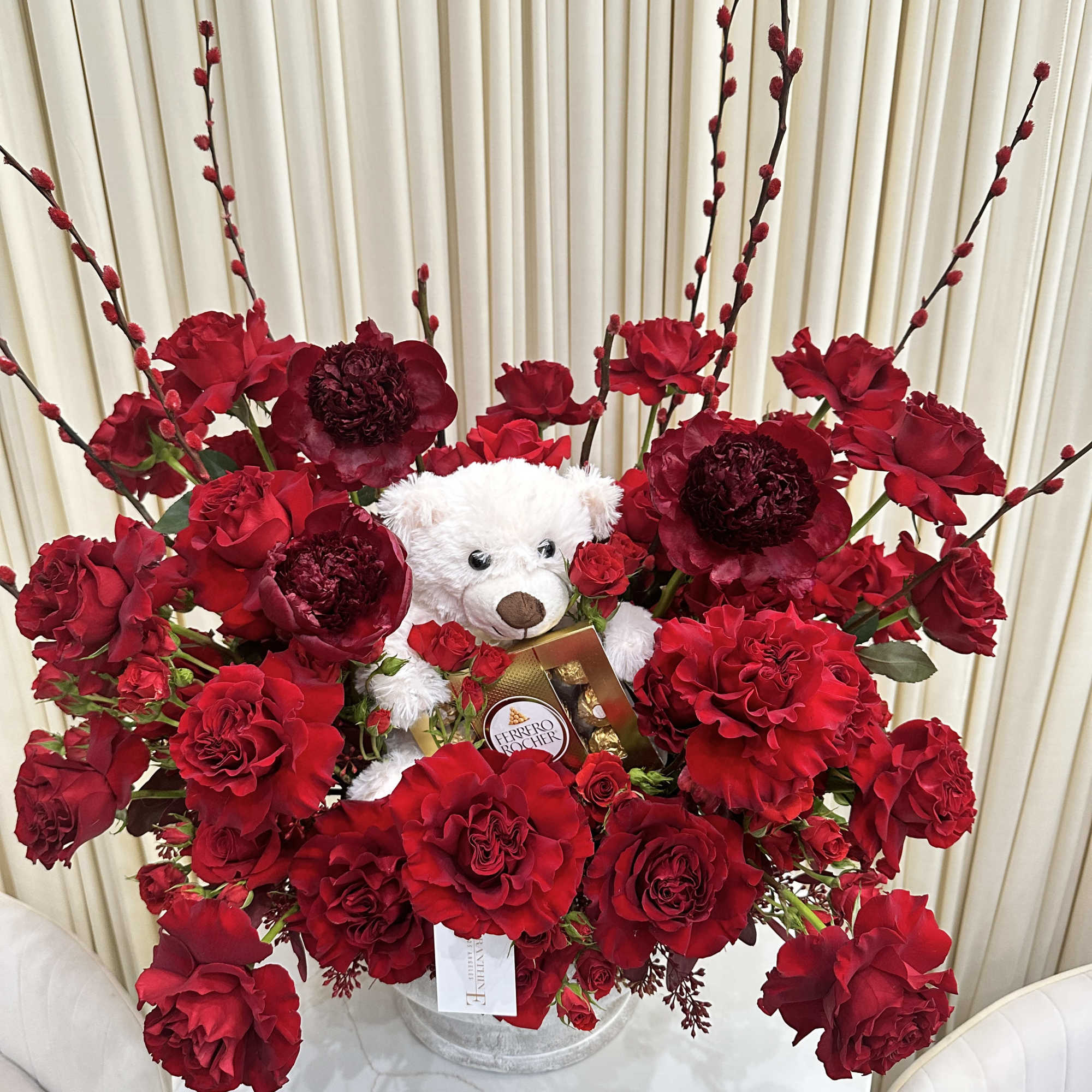 This delightful arrangement features a cuddly white teddy bear nestled amidst a
