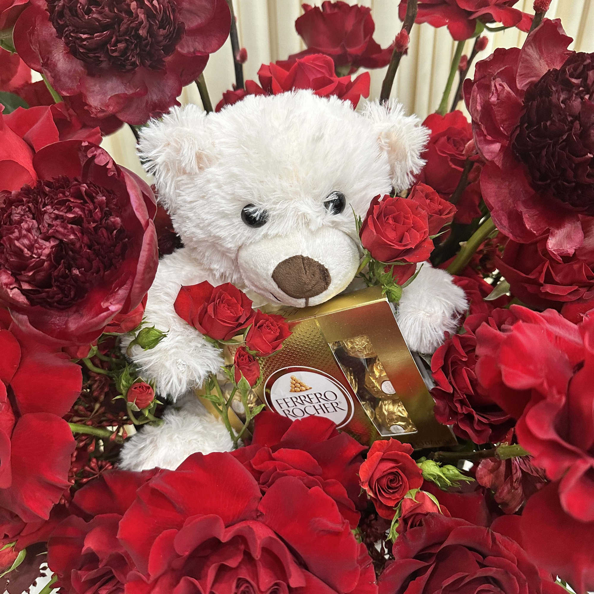 This delightful arrangement features a cuddly white teddy bear nestled amidst a