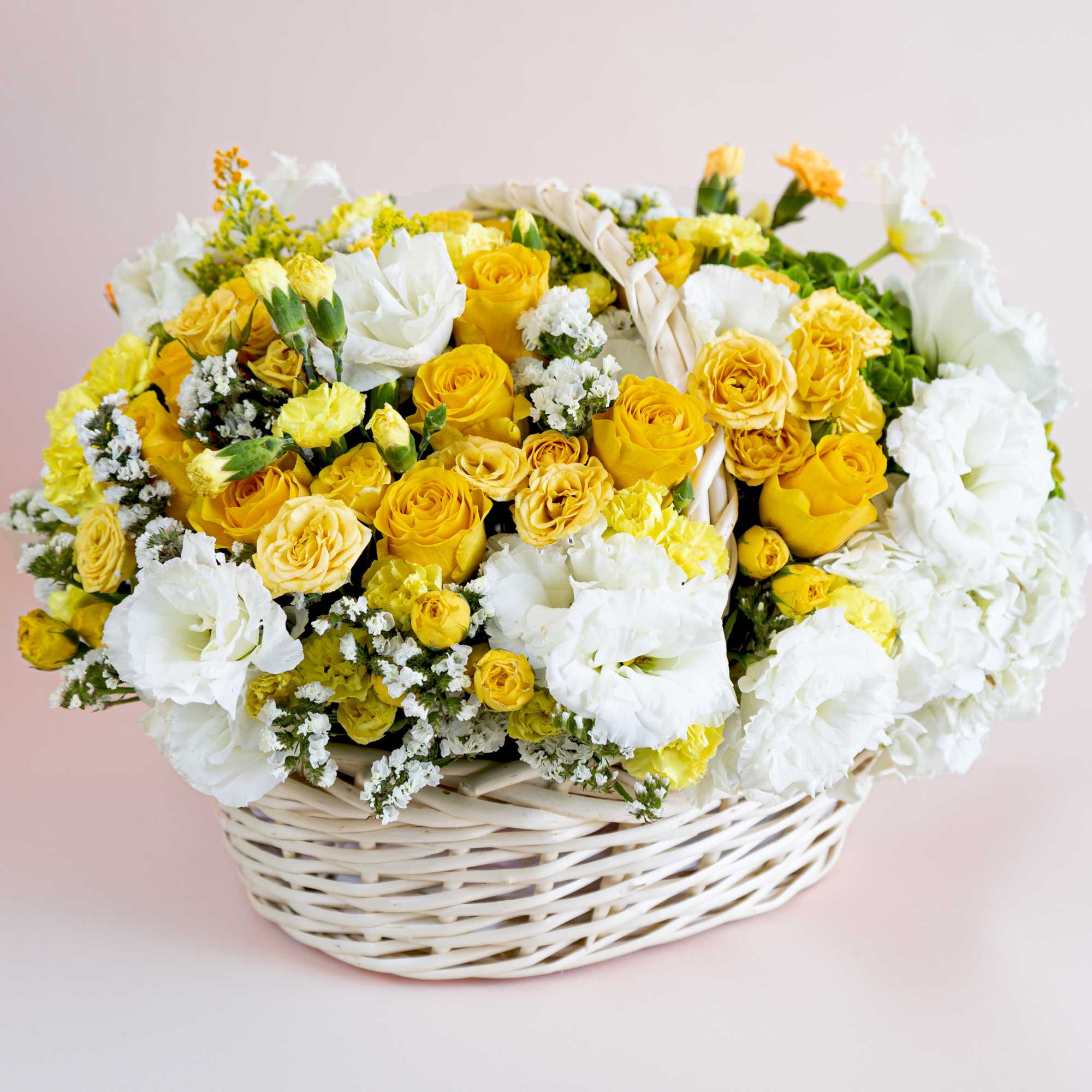 A handled white bamboo basket holds fresh elegant yellow roses, soft yellow