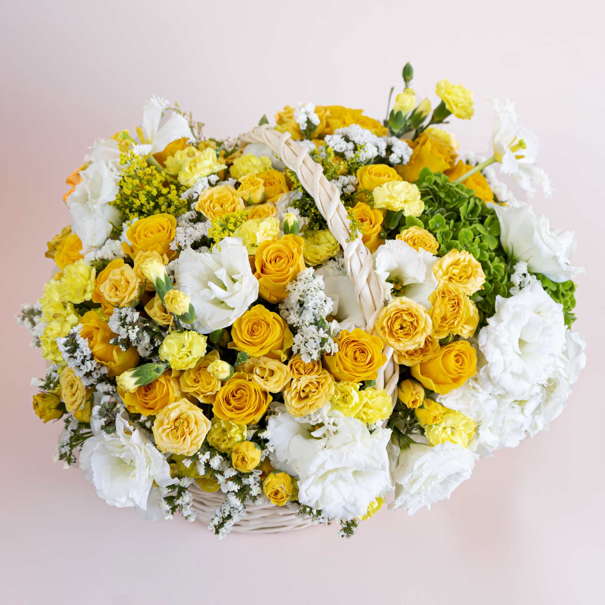 A handled white bamboo basket holds fresh elegant yellow roses, soft yellow
